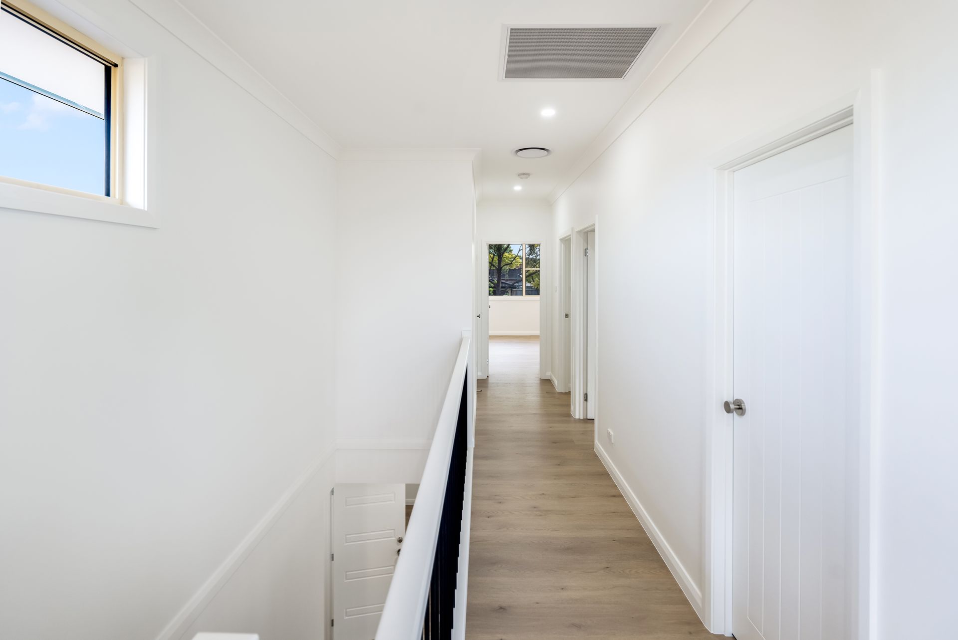 Bright White Hallway With Wood Flooring, Doors on the Right — Matt Made Building in Camden, NSW