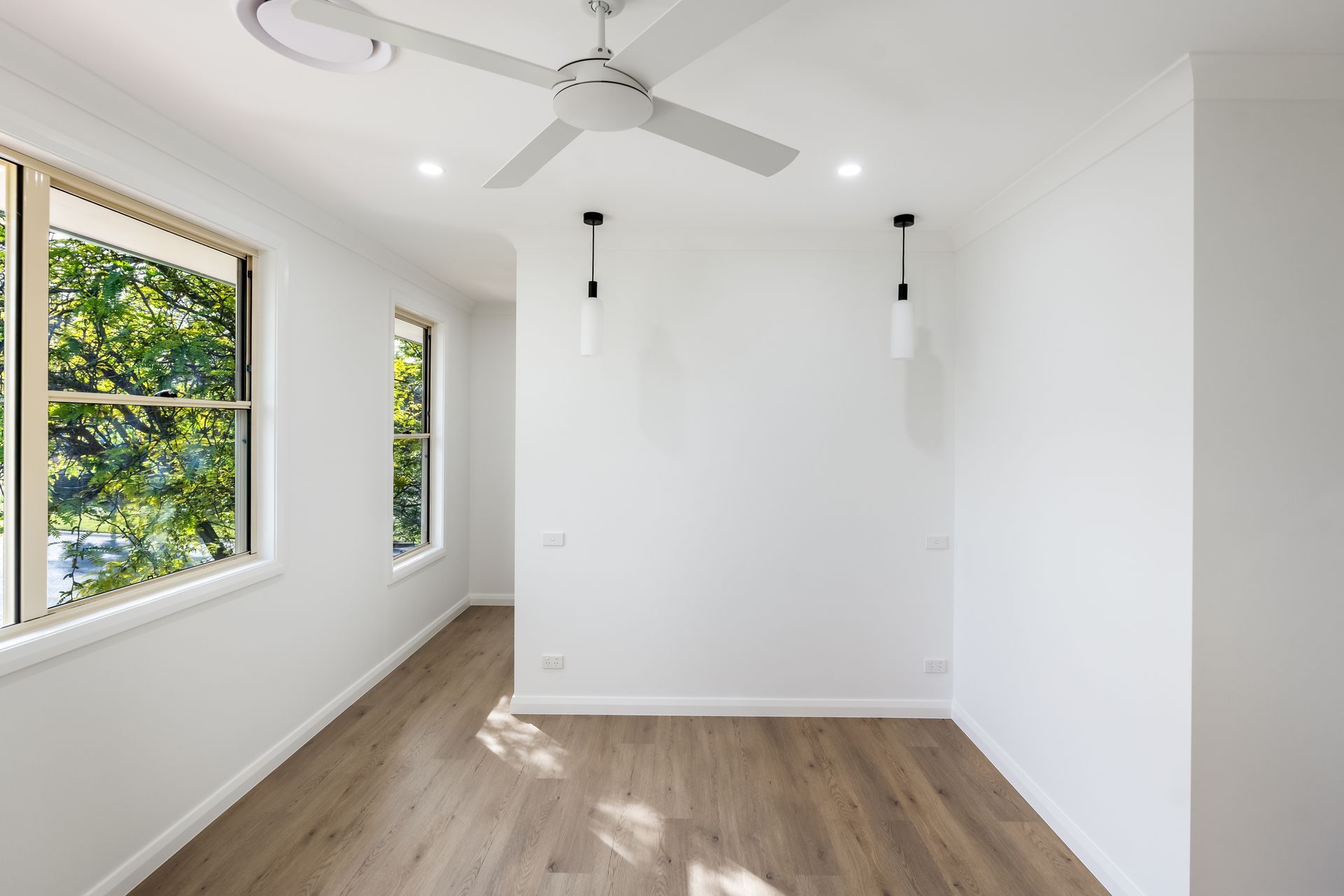 Bright Empty Bedroom With White Walls, Wood Floors and Wall Sconces — Matt Made Building in Camden, NSW
