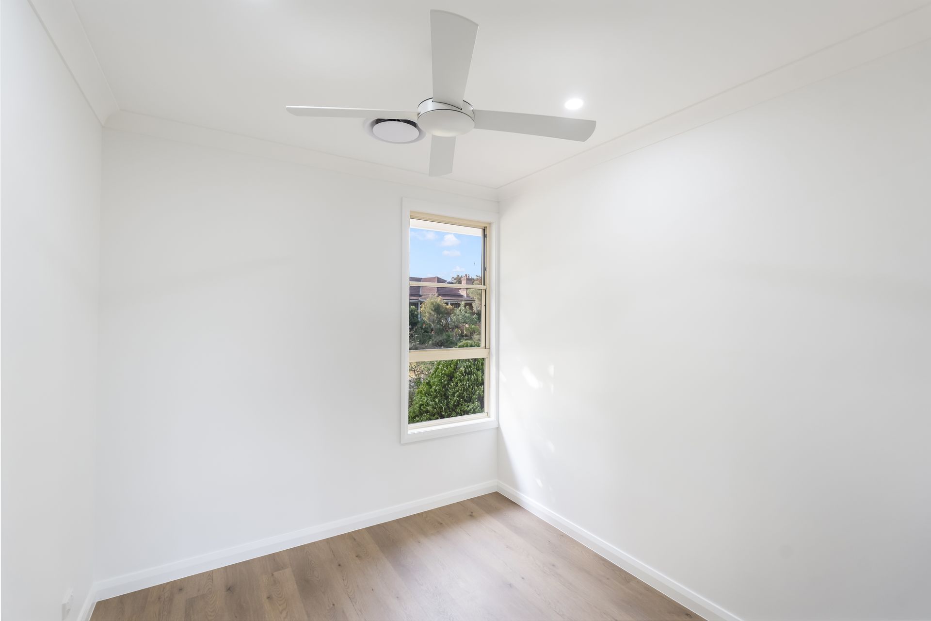 Empty White Bedroom With a Ceiling Fan, Wood Floor, and Narrow Window — Matt Made Building in Camden, NSW