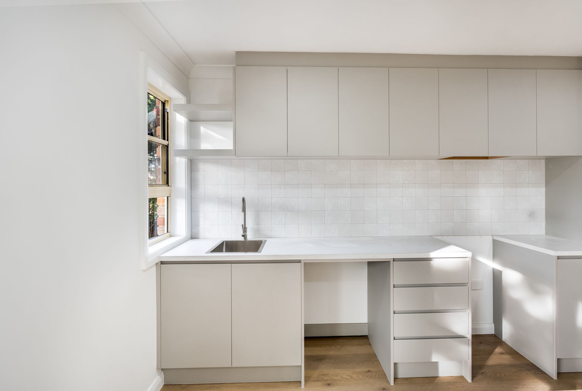 Bright White Minimalist Kitchen With Cabinets, Sink, Drawers, and Wooden Floor — Matt Made Building in Camden, NSW