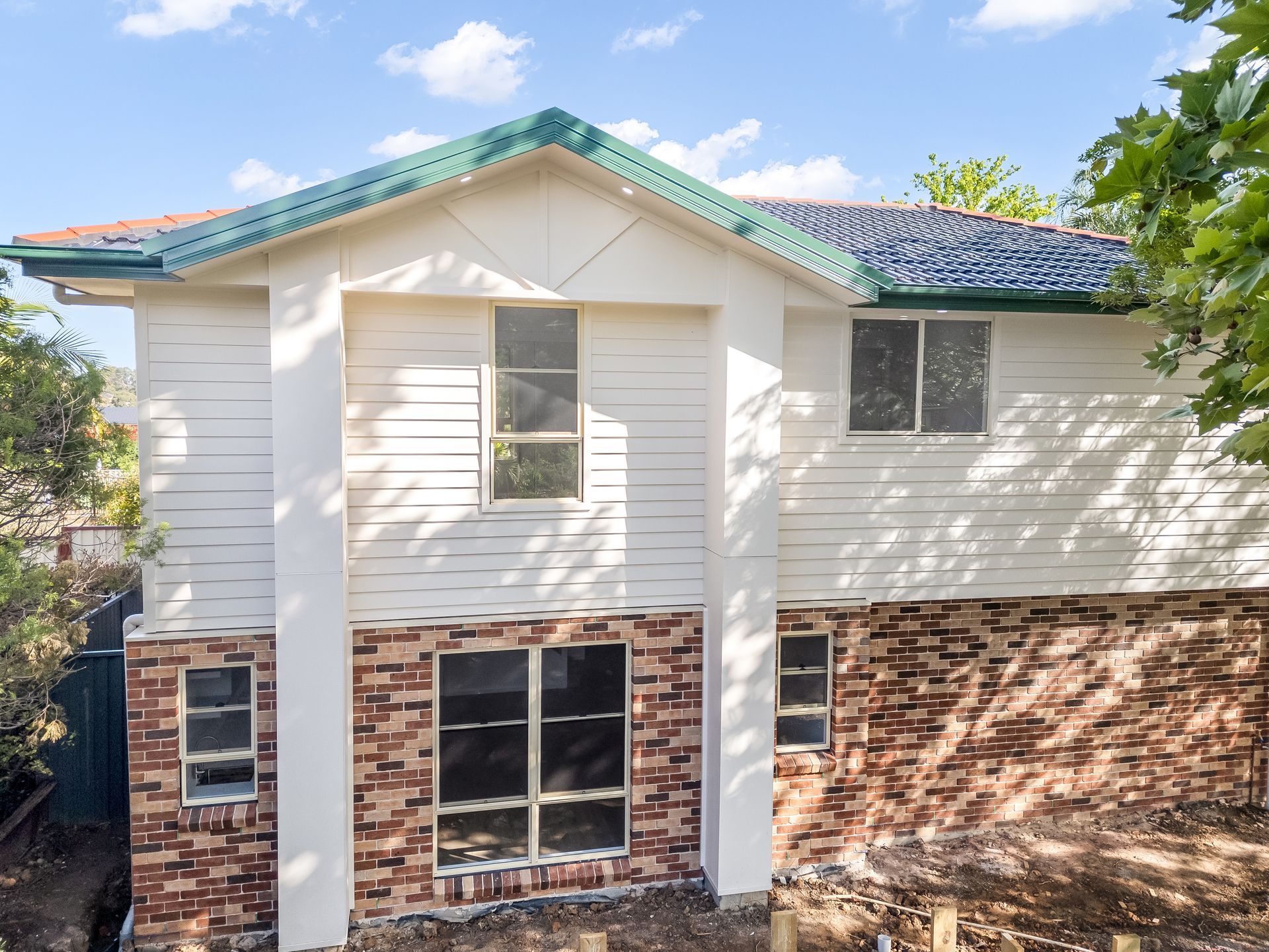 Two-story House With White Siding and a Green Roof Under a Blue Sky — Matt Made Building in Camden, NSW