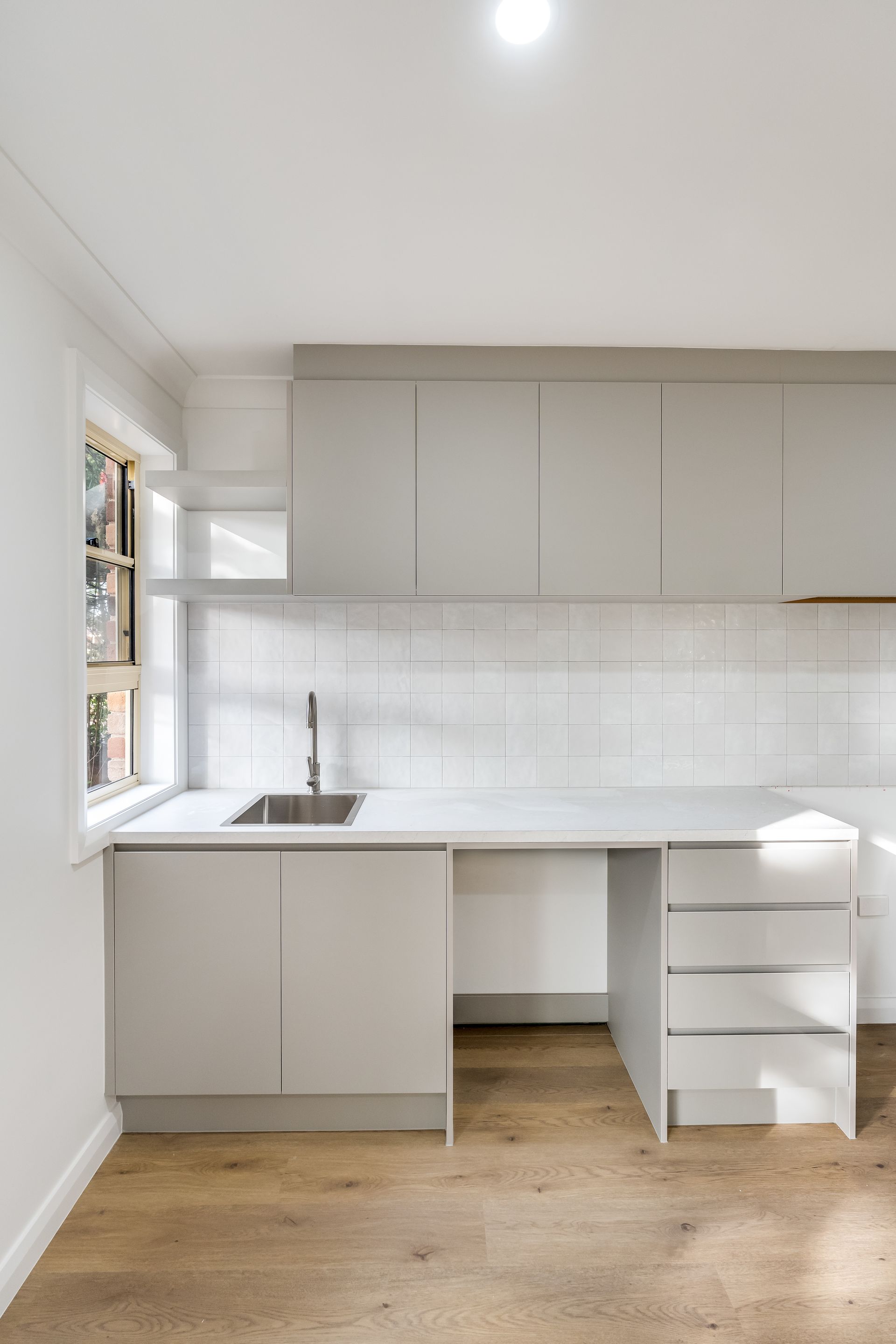 Bright Minimalist Kitchen With Light Wood Floor and Gray Upper Cupboards — Matt Made Building in Camden, NSW