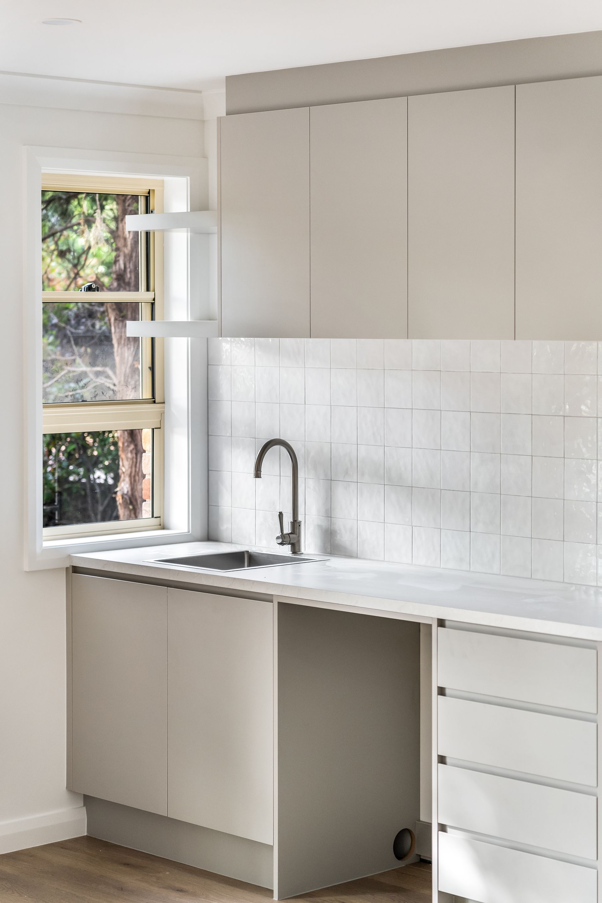 Modern White Kitchen With Sink, Cabinets and a Window Over the Counter — Matt Made Building in Camden, NSW