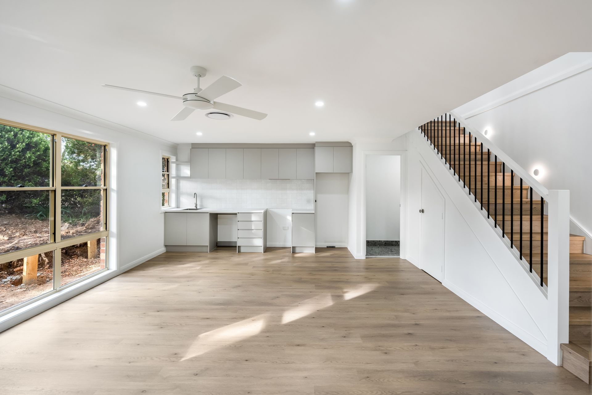 Bright Empty Living Room With Open Kitchen and a Staircase With White Railing — Matt Made Building in Camden, NSW