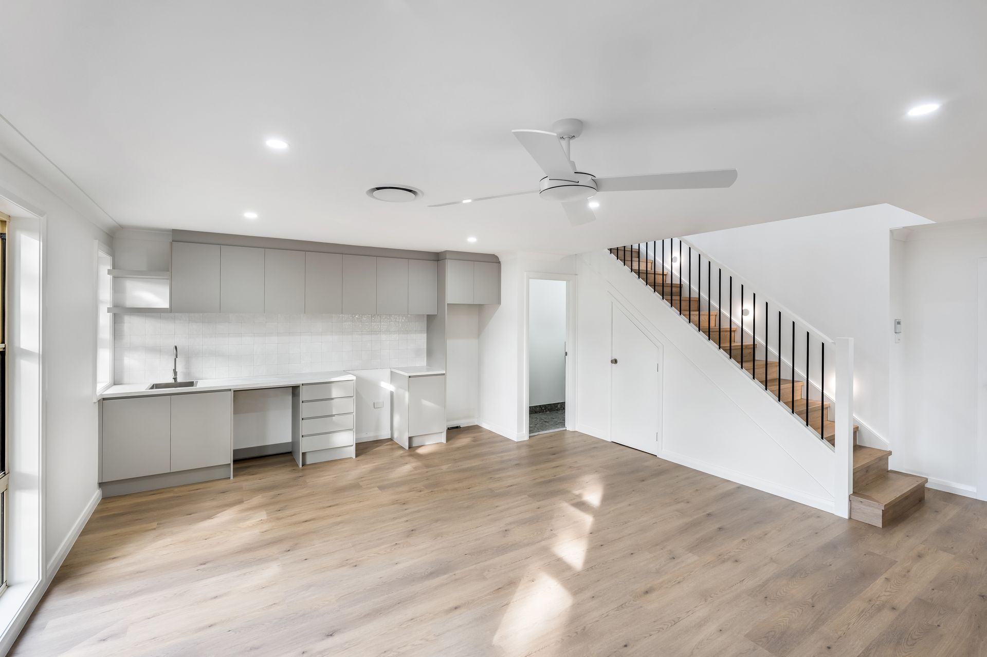 Bright Open Living Room With White Kitchen and Staircase on the Right — Matt Made Building in Camden, NSW