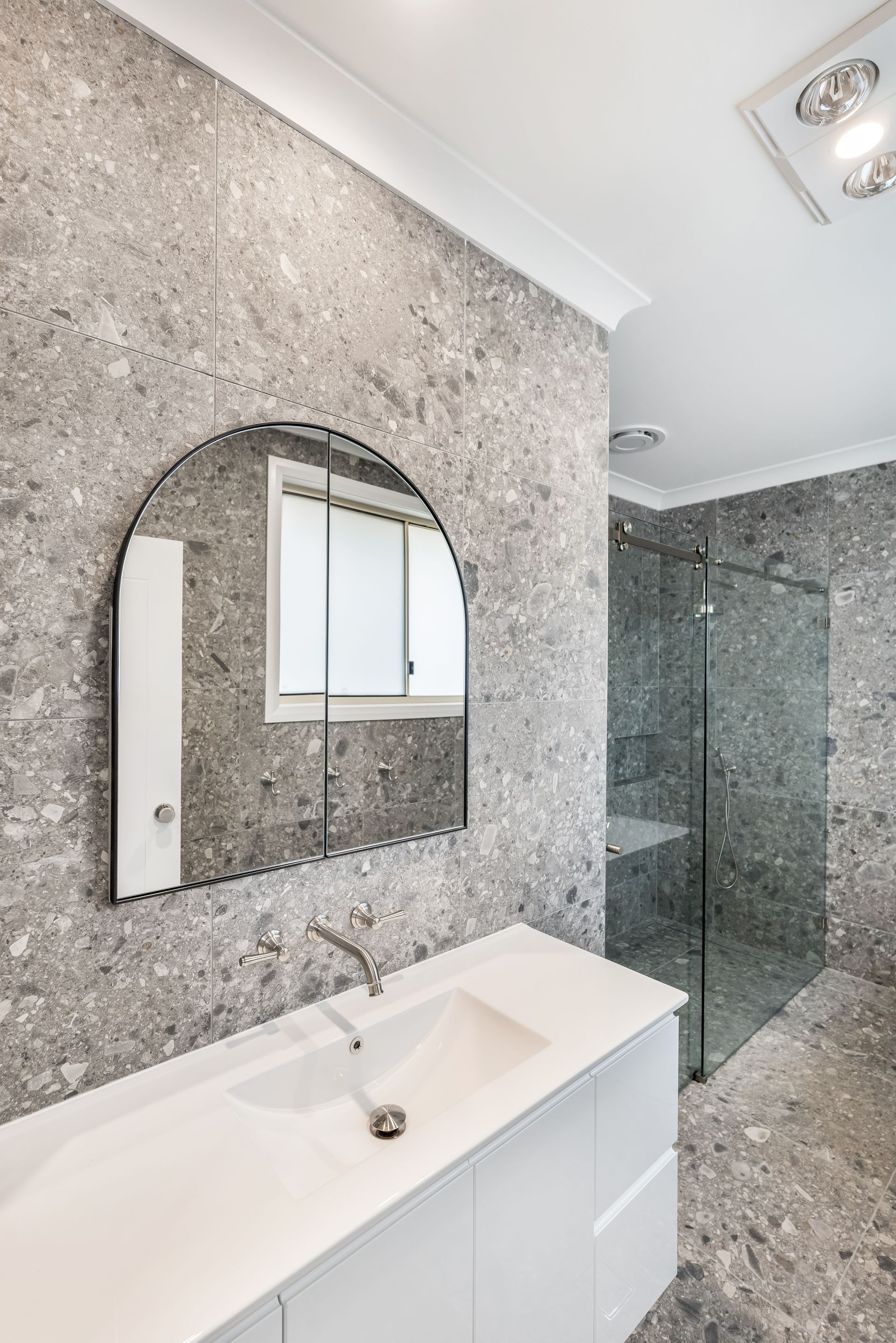 Modern Bathroom With Speckled Stone Walls and Glass Shower Enclosure — Matt Made Building in Camden, NSW
