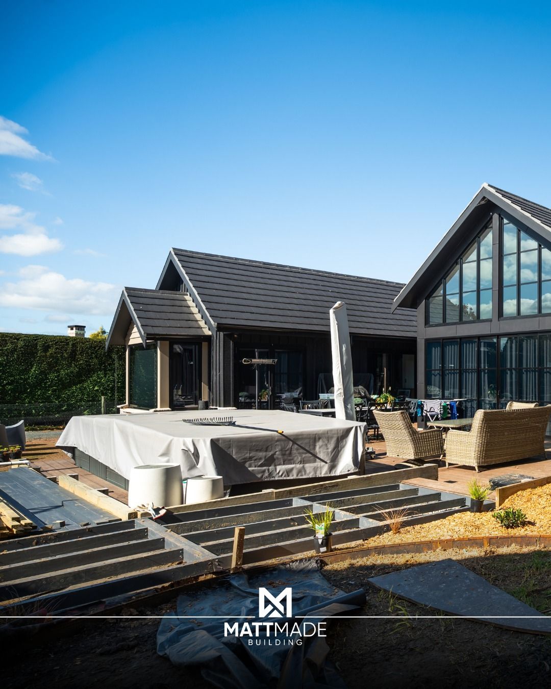 Modern house under construction with white tarp, dark roof, and blue sky — Matt Made Building in Campbelltown, NSW