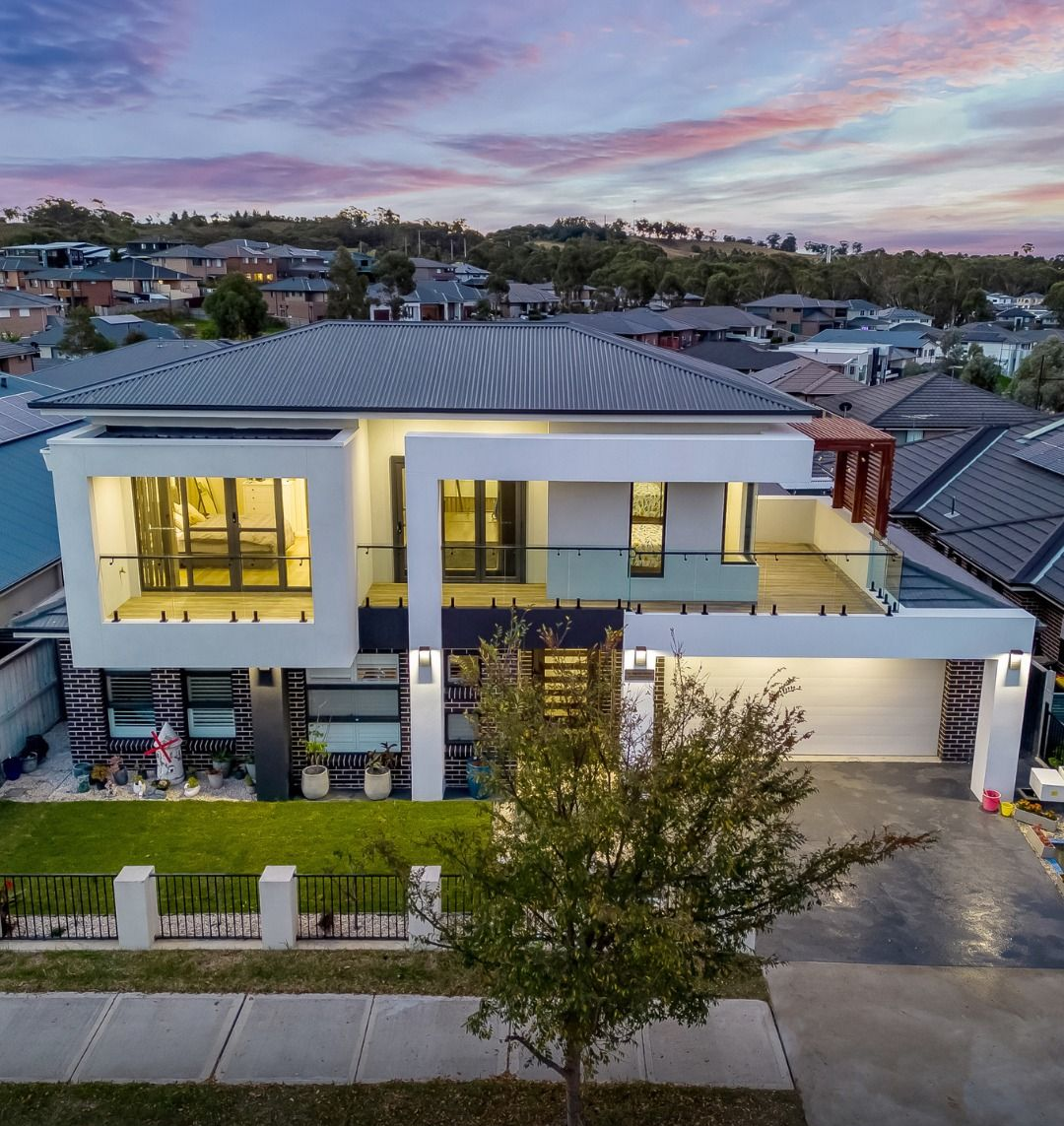 Modern two-story home at dusk with warm lit windows and a balcony, seen from the street  — Matt Made Building in Camden, NSW