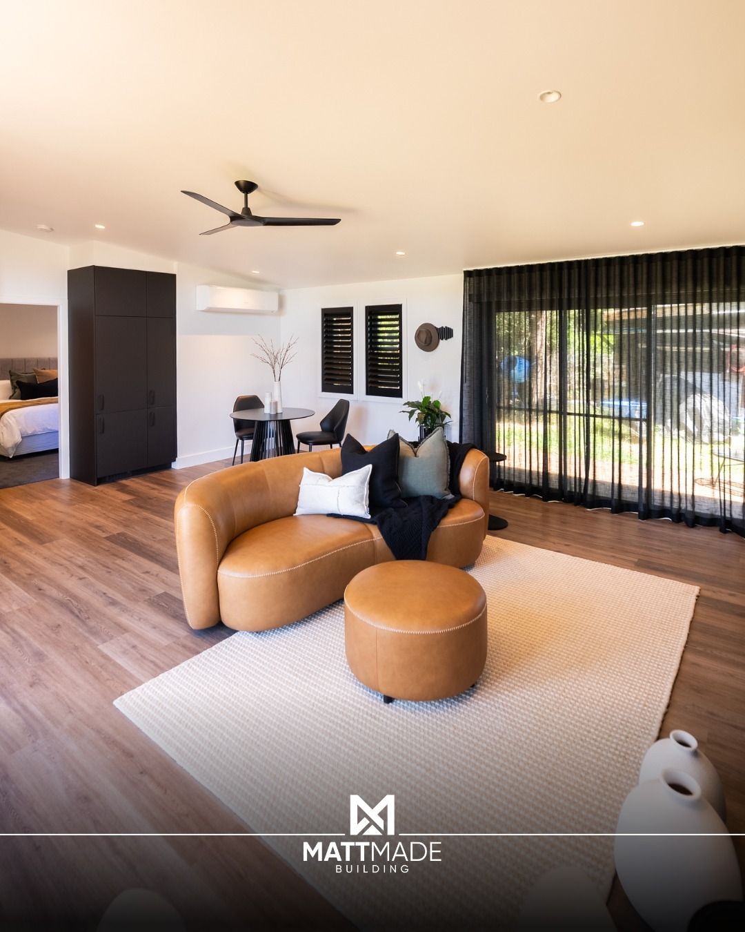 A Modern Living Room With A Curved Tan Leather Sofa — Matt Made Building in Southern Highlands, NSW