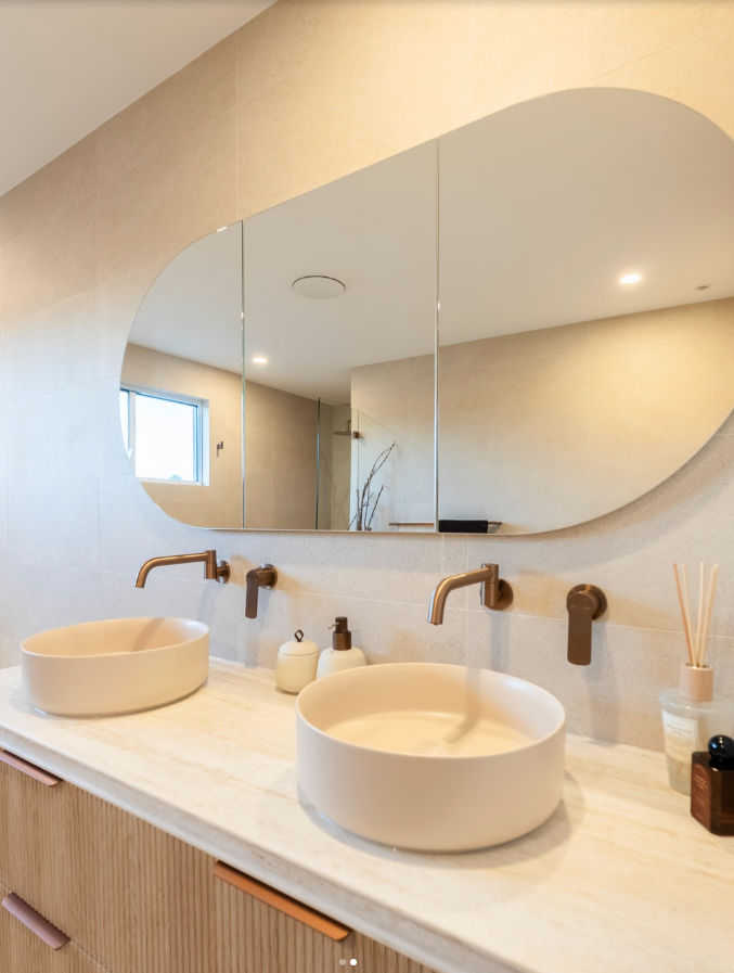 Modern bathroom vanity with round sink, wooden faucets and an oval mirror on a marble countertop - Matt Made Building - Builder Camden, NSW.