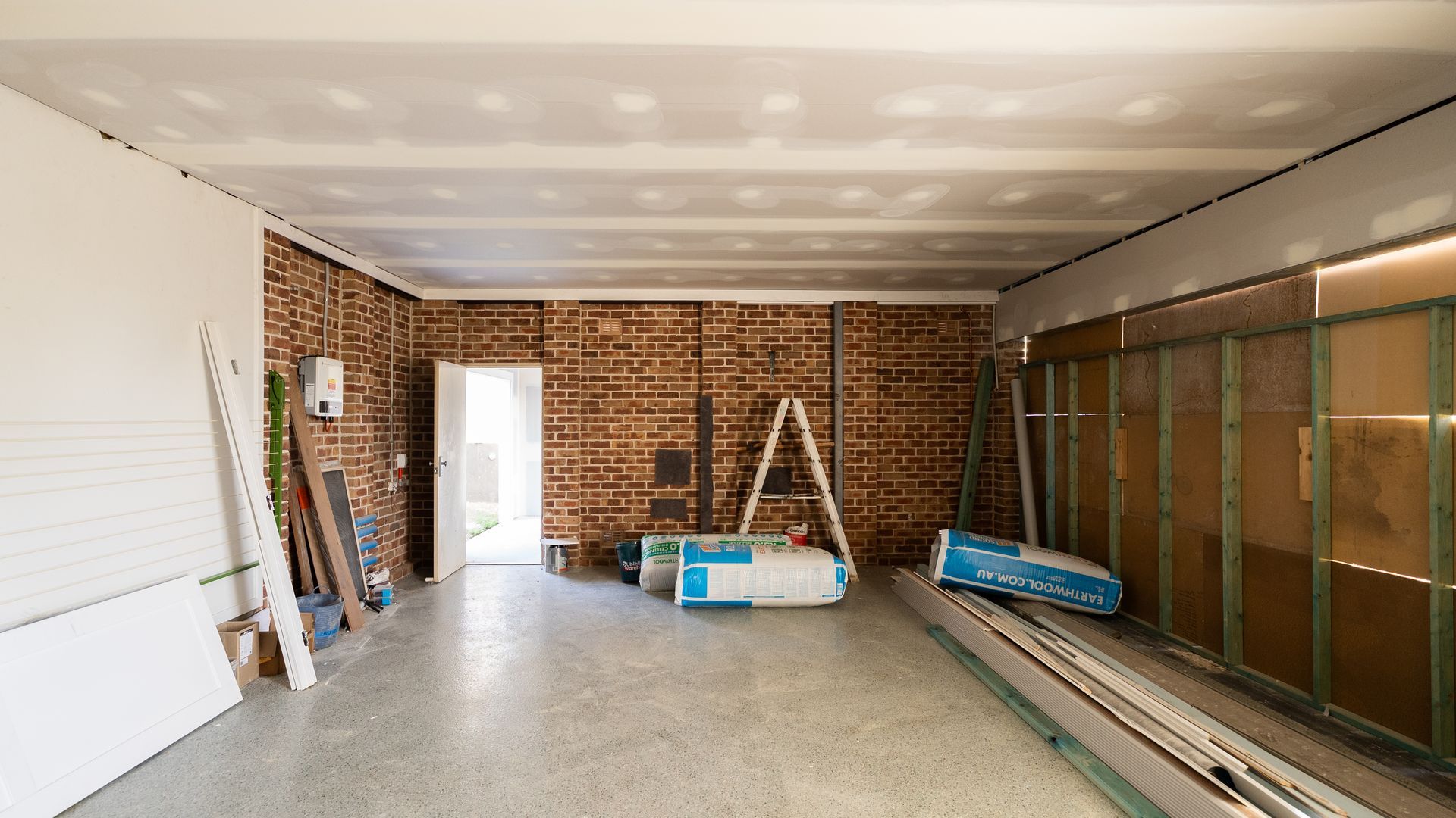 Empty Unfinished Room With Brick Wall and Stacked Building Materials — Matt Made Building in Camden, NSW