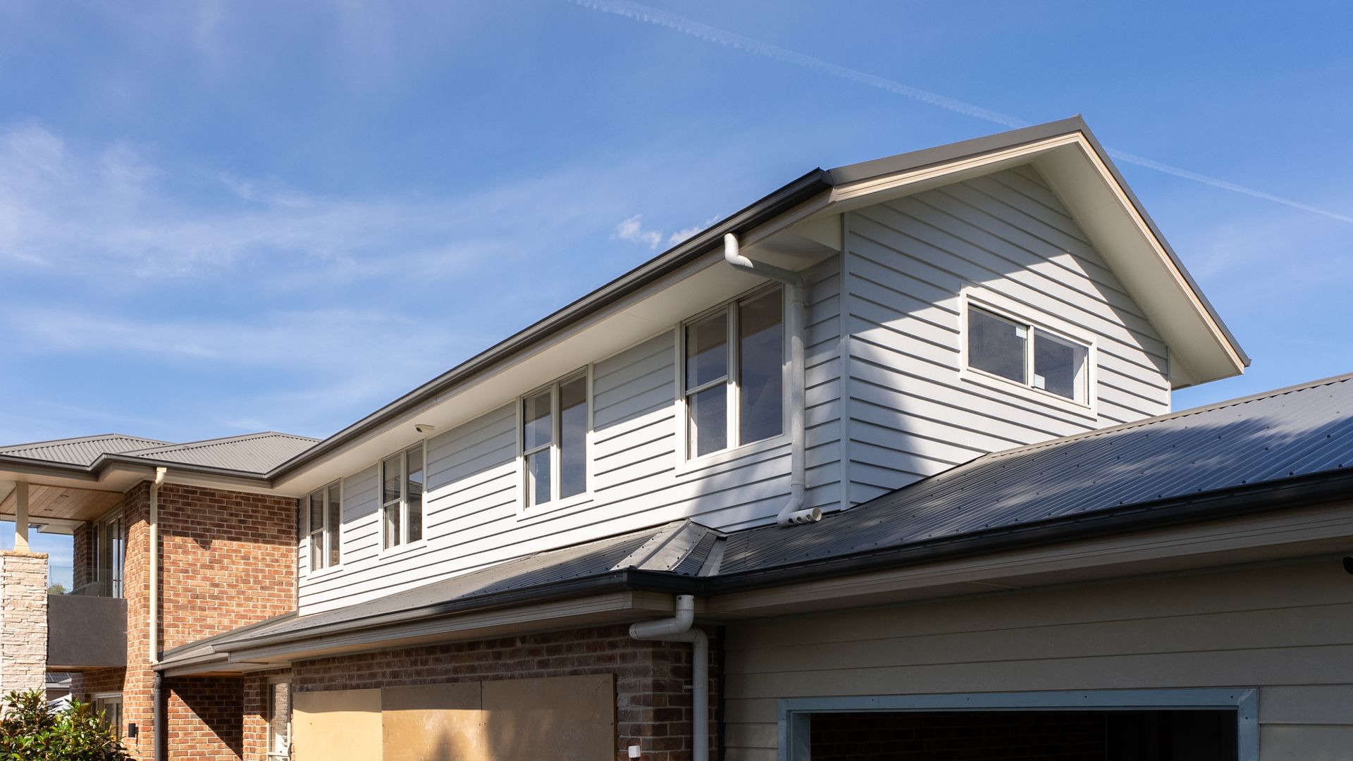 Two-story Suburban House With White Siding and a Dark Roof Under a Blue Sky — Matt Made Building in Camden, NSW