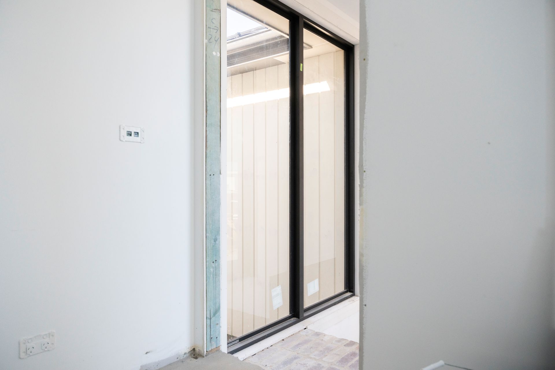 Empty White Room With a Black-framed Sliding Glass Door to a Balcony or Patio — Matt Made Building in Camden, NSW