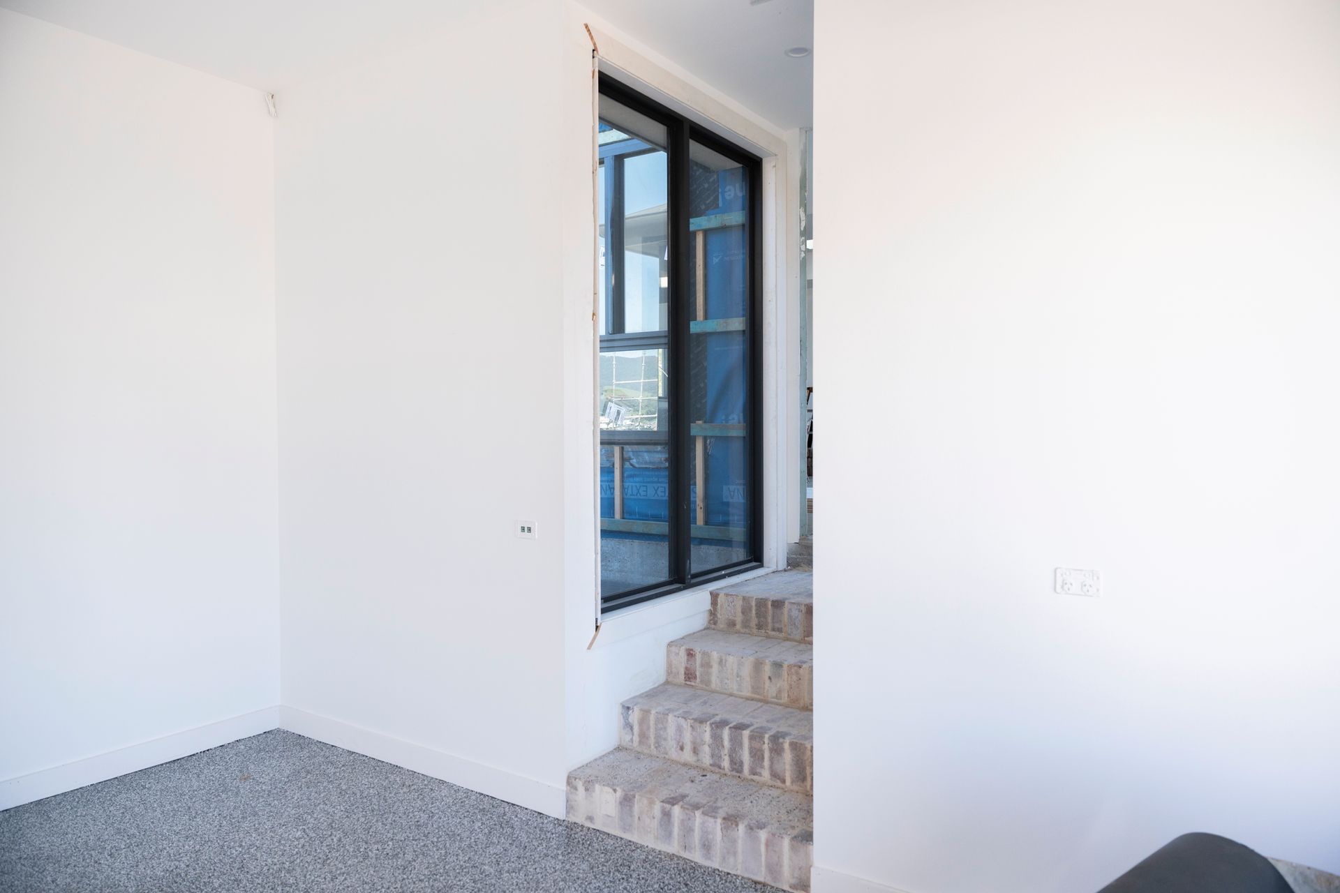 Empty White Room With Carpet, Stairs, and a Glass Doorway to a Balcony — Matt Made Building in Camden, NSW
