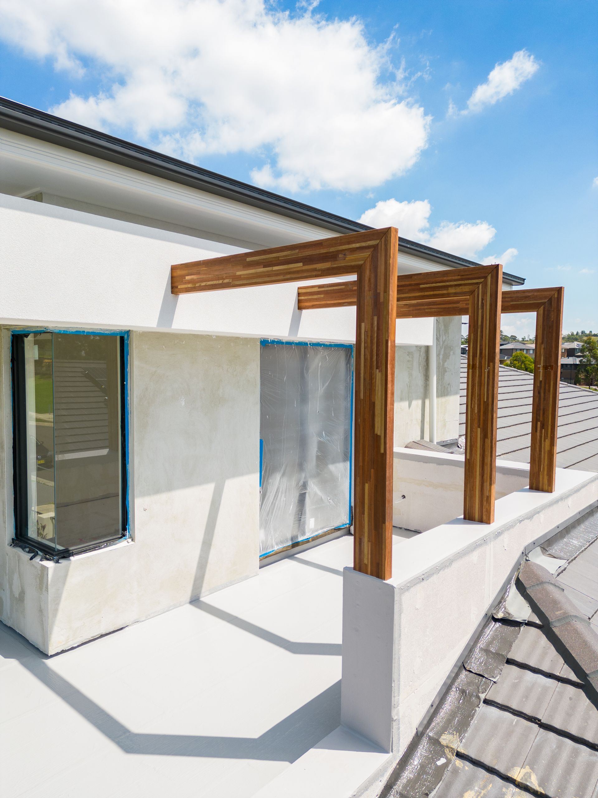 Modern White Building With Wooden Pergola Shades Along a Walkway — Matt Made Building in Camden, NSW
