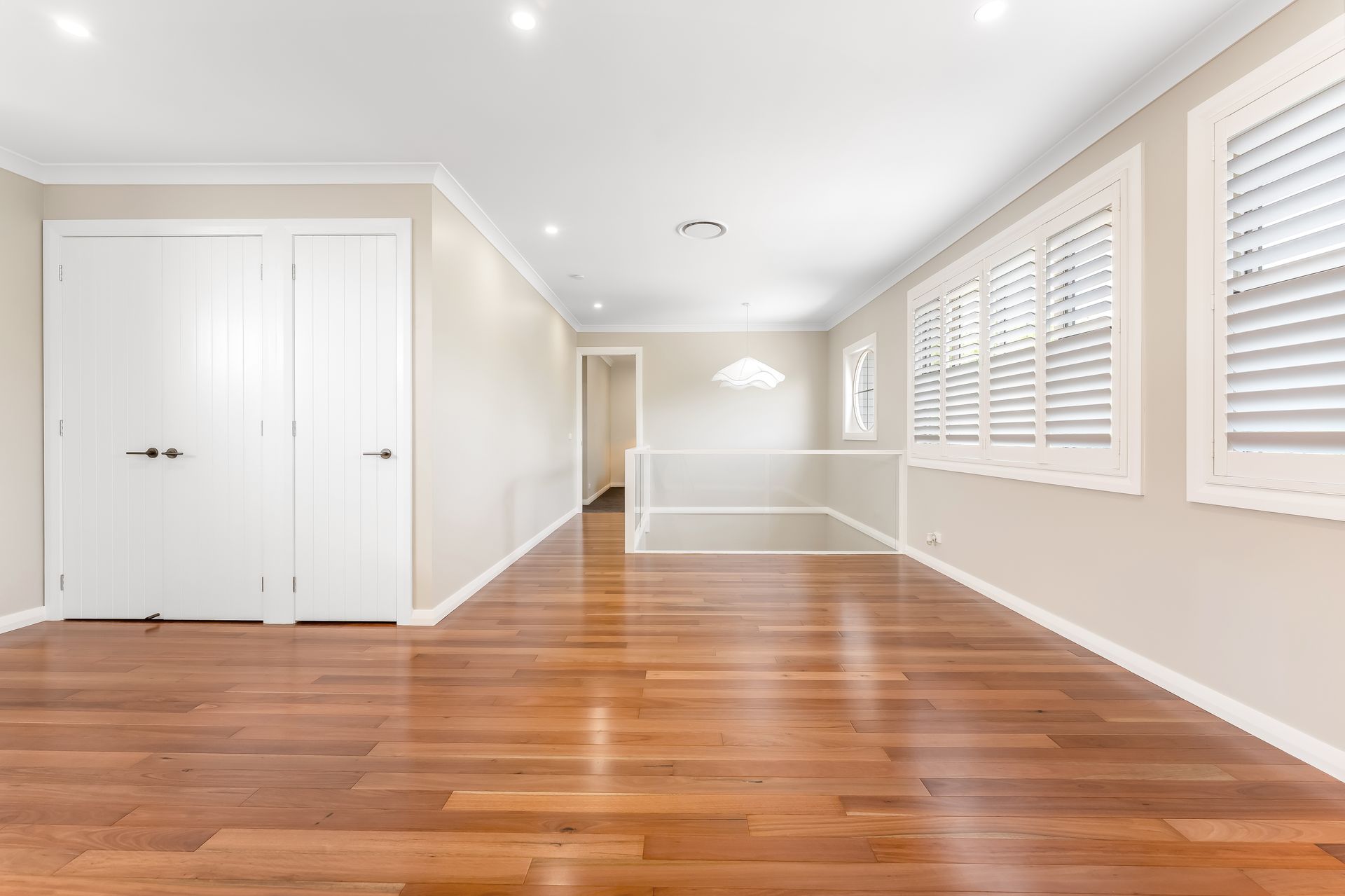 Bright Empty Living Room With Hardwood Floors and Large Windows With Shutters — Matt Made Building in Camden, NSW