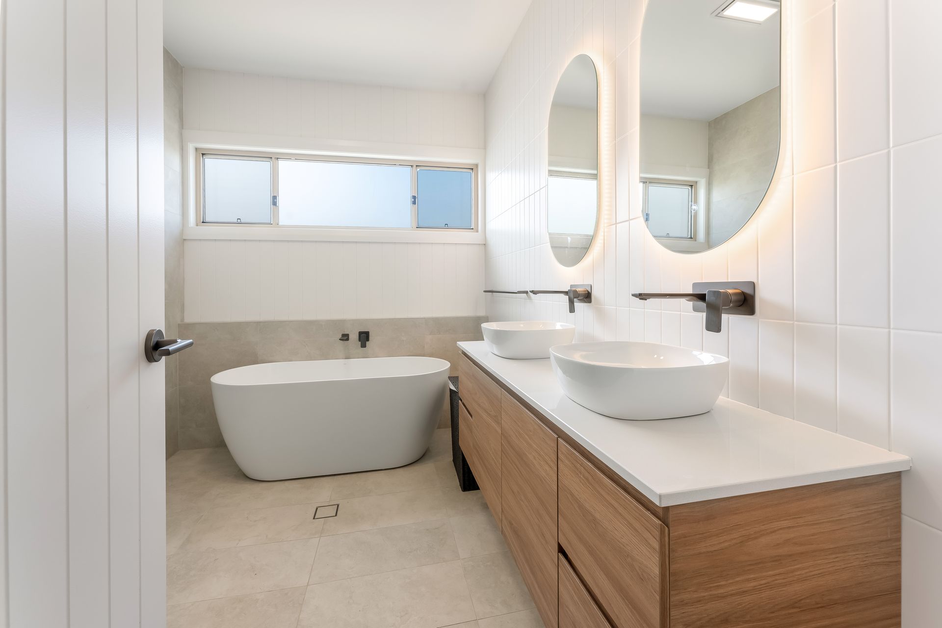 Modern Bathroom With Freestanding Tub and Round Mirror Under a Window — Matt Made Building in Camden, NSW