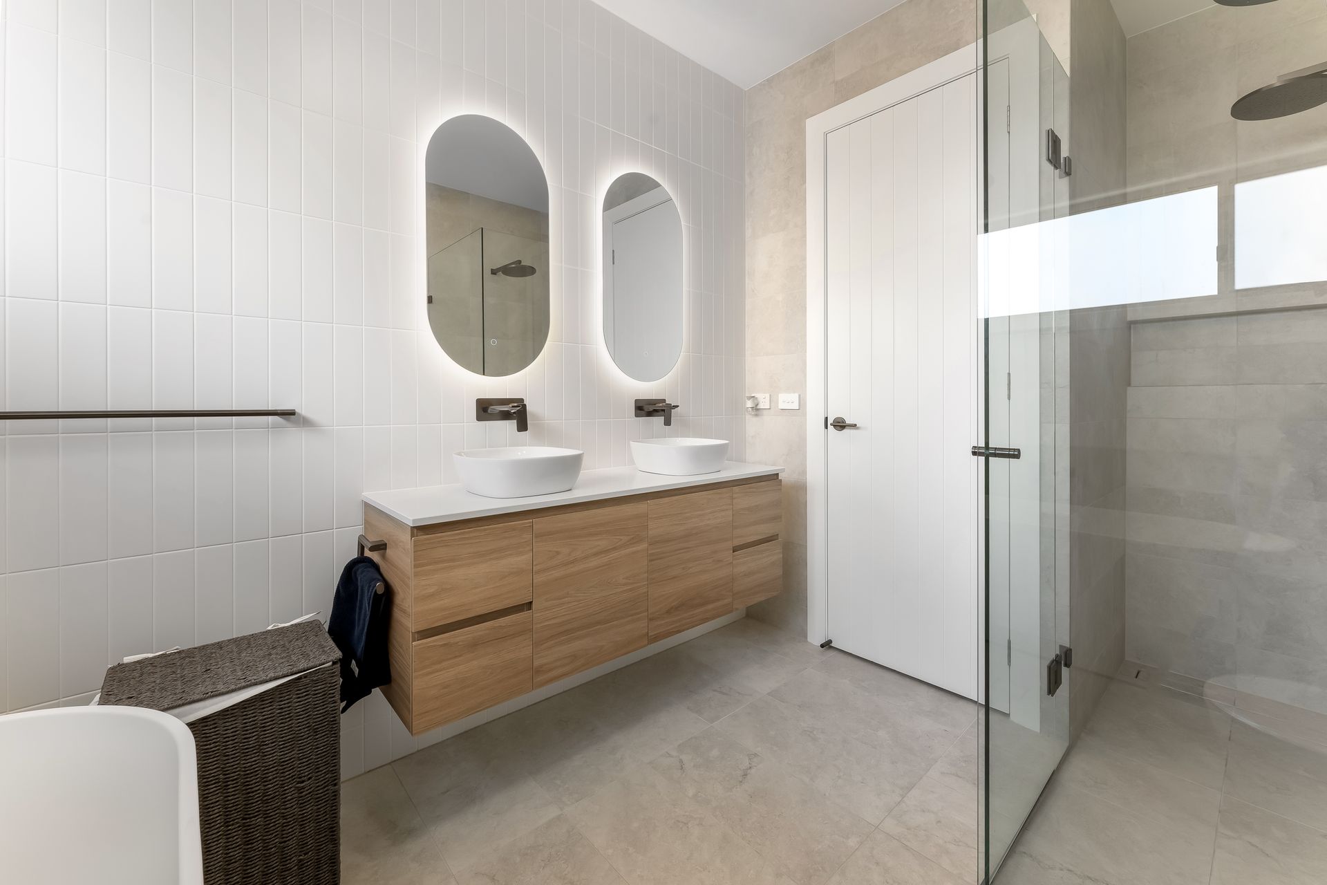 Modern Bathroom With Wooden Vanity, Double Mirrors and Light Tiled Walls — Matt Made Building in Camden, NSW