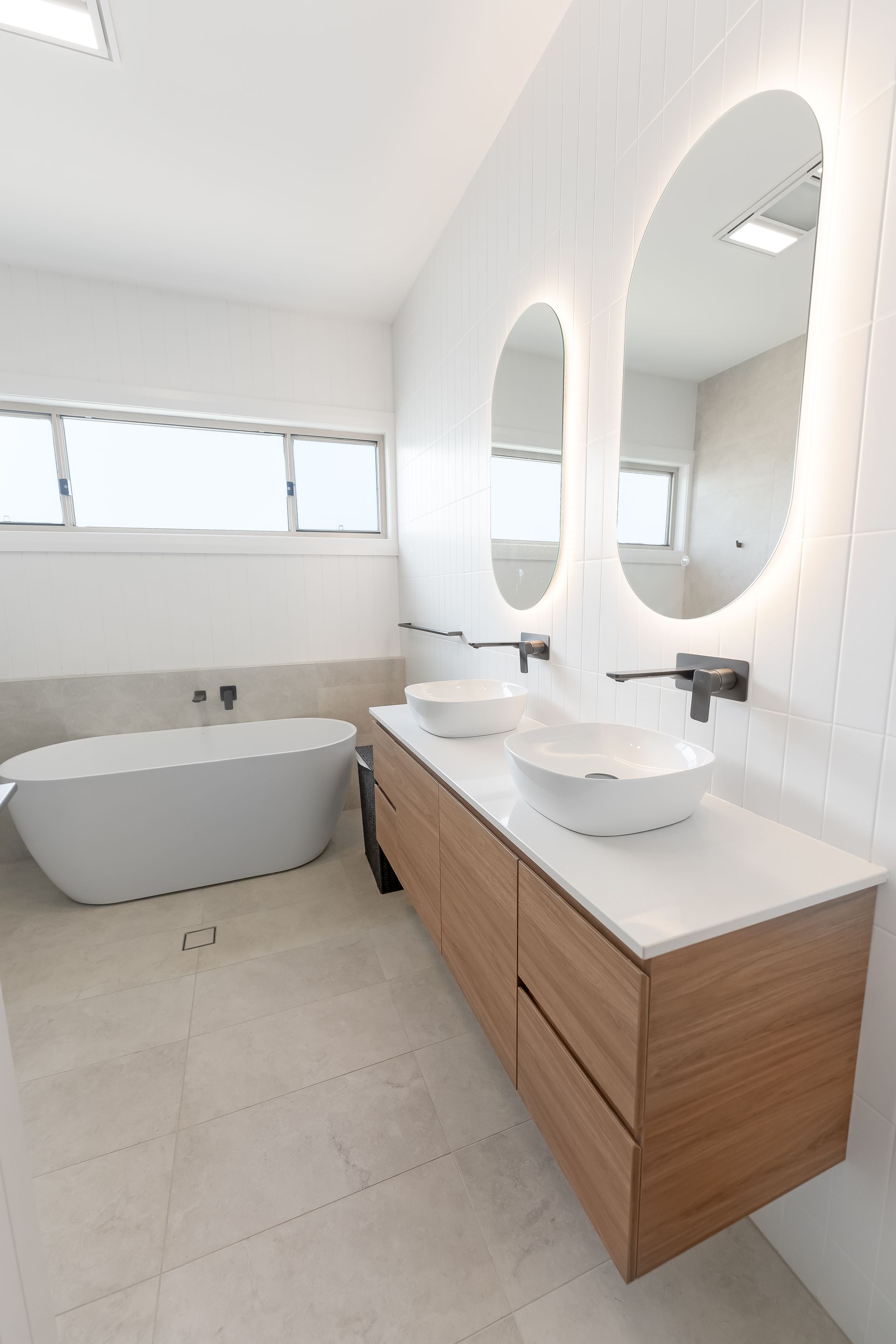Bright Modern Bathroom With Freestanding Tub and Large Oval Mirrors — Matt Made Building in Camden, NSW