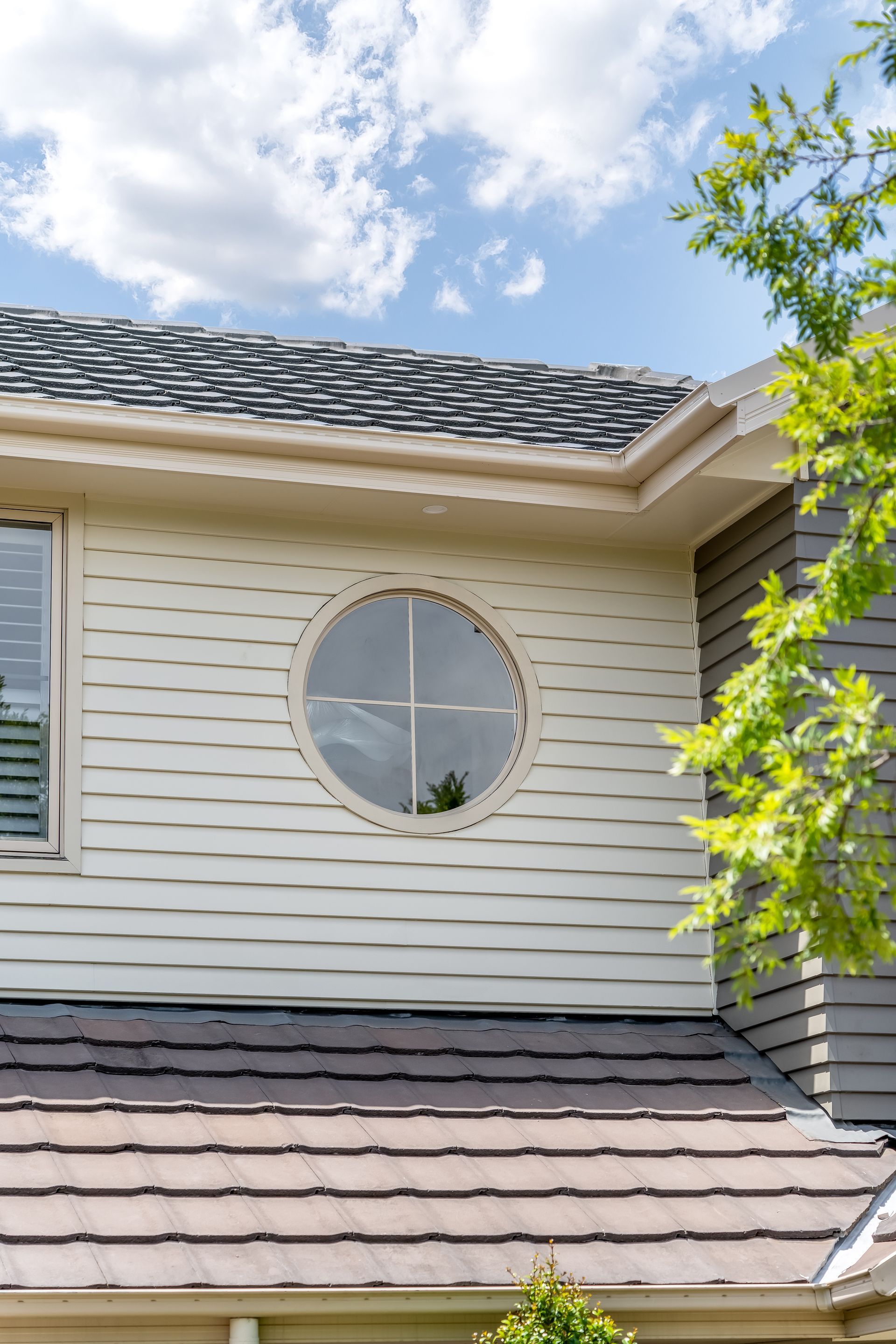 Exterior of a Beige House With a Round Window and Blue Sky With Clouds — Matt Made Building in Camden, NSW