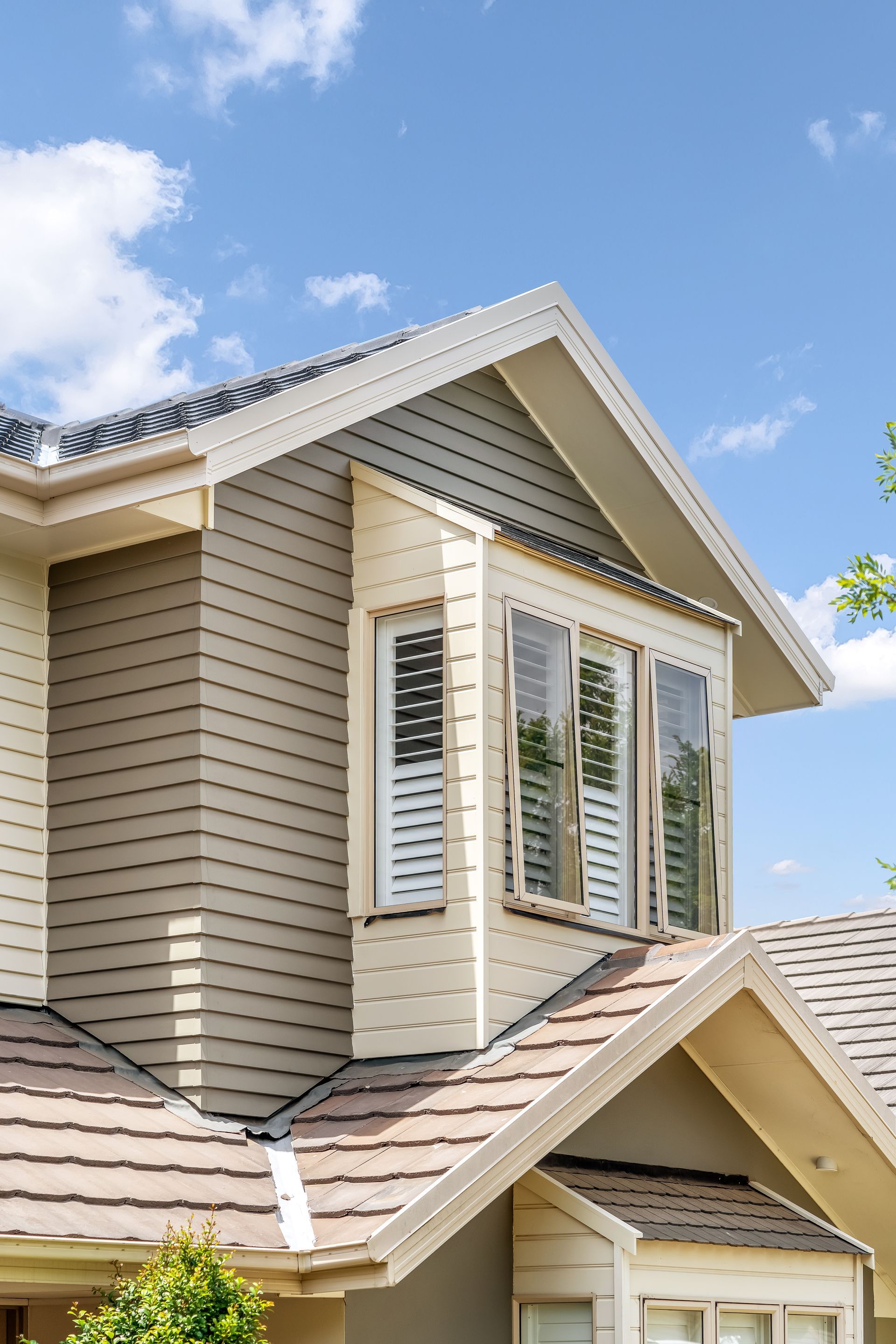 Tan House Exterior With White Trim and Bay Window Against a Blue Sky — Matt Made Building in Camden, NSW