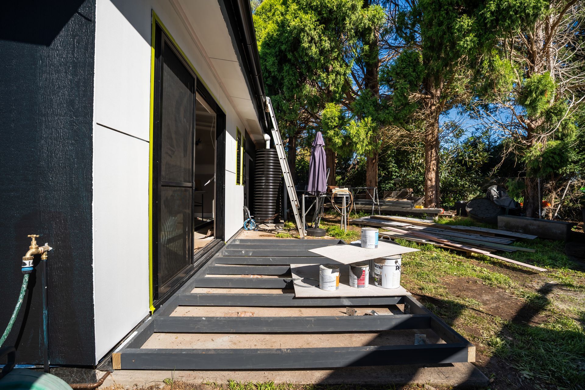 Sunny Backyard Patio With White Table and Umbrella Beside a Modern House — Matt Made Building in Camden, NSW