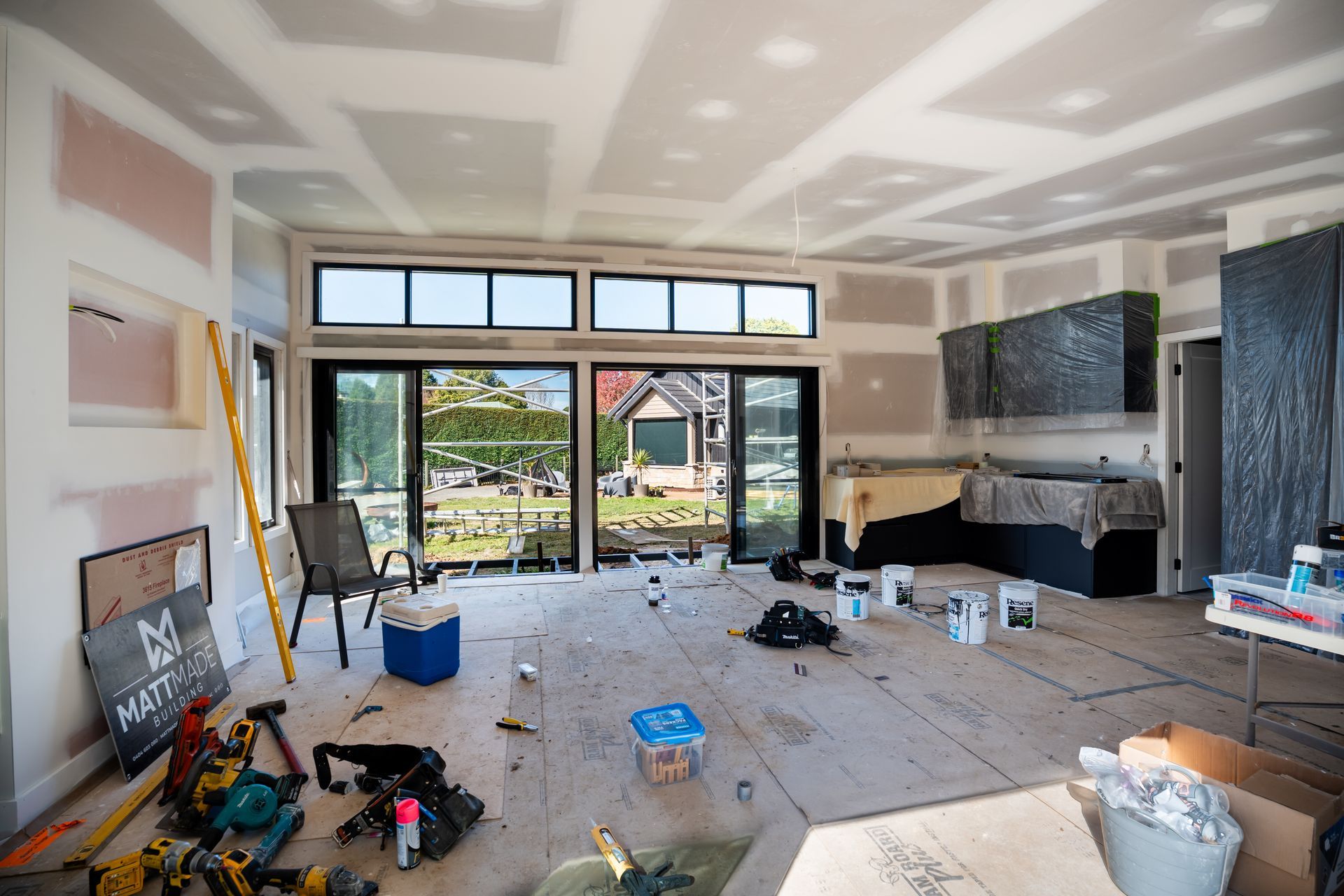 Living Room Under Renovation With Tools and Large Windows Overlooking a Yard — Matt Made Building in Camden, NSW