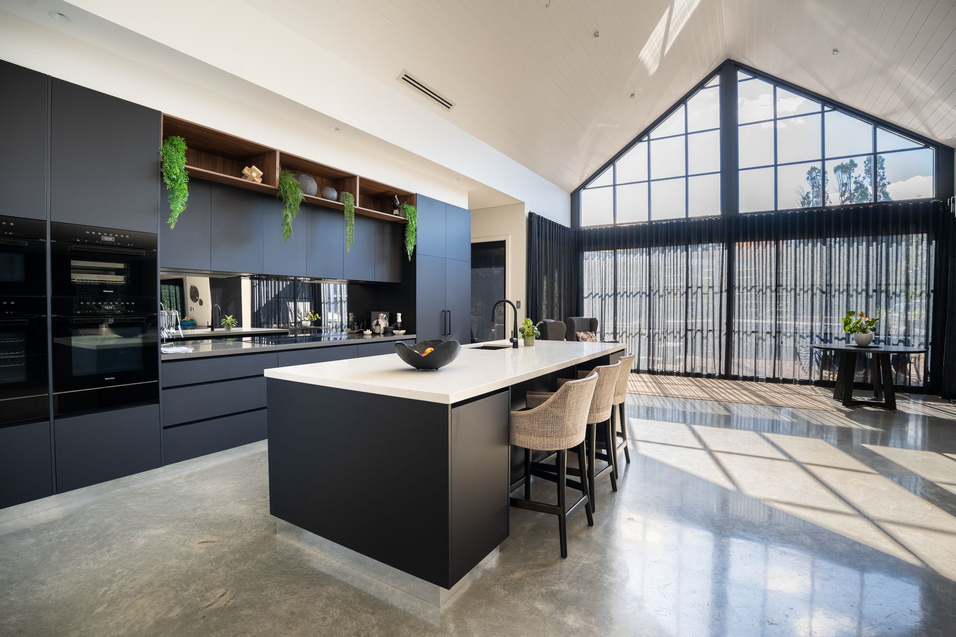 Modern Kitchen With Dark Cabinetry and Tall Windows Filling the Bright Room — Matt Made Building in Camden, NSW