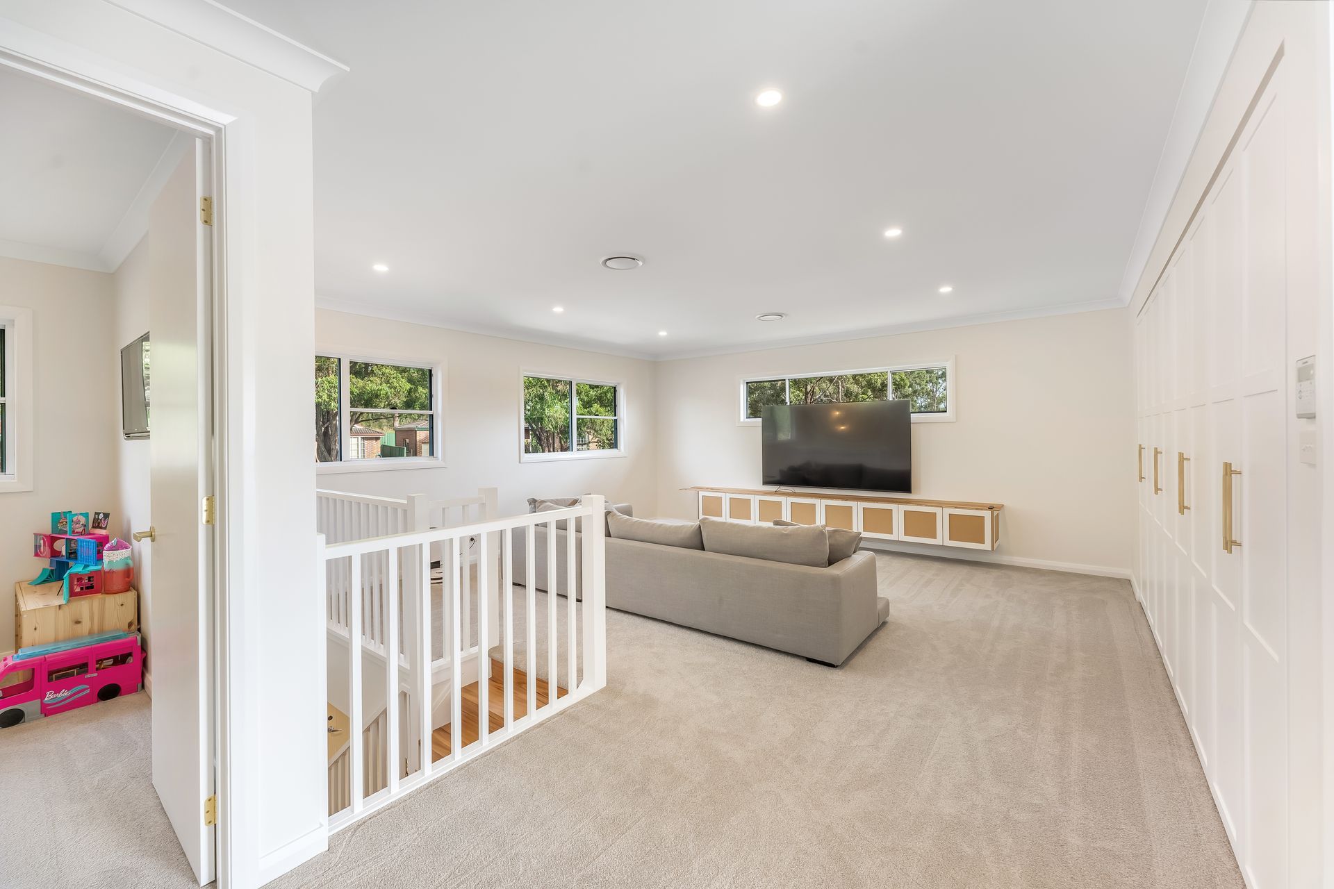 Bright Upstairs Lounge With Beige Sofa, White Walls and a Stair Railing — Matt Made Building in Camden, NSW