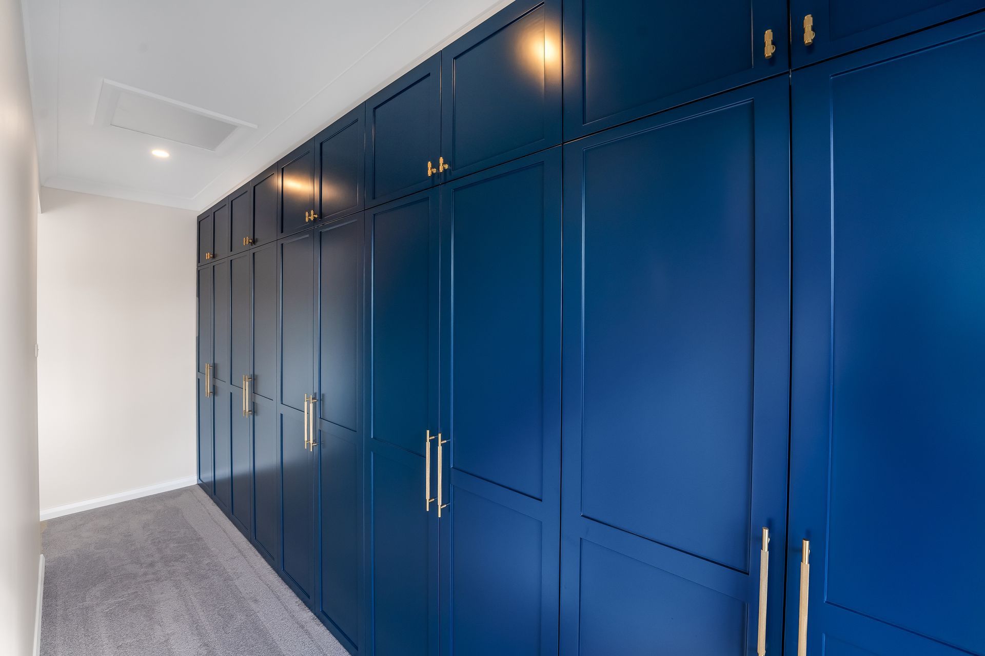 Blue Built-in Hallway Cabinets With Brass Handles Along a Carpeted Corridor — Matt Made Building in Camden, NSW