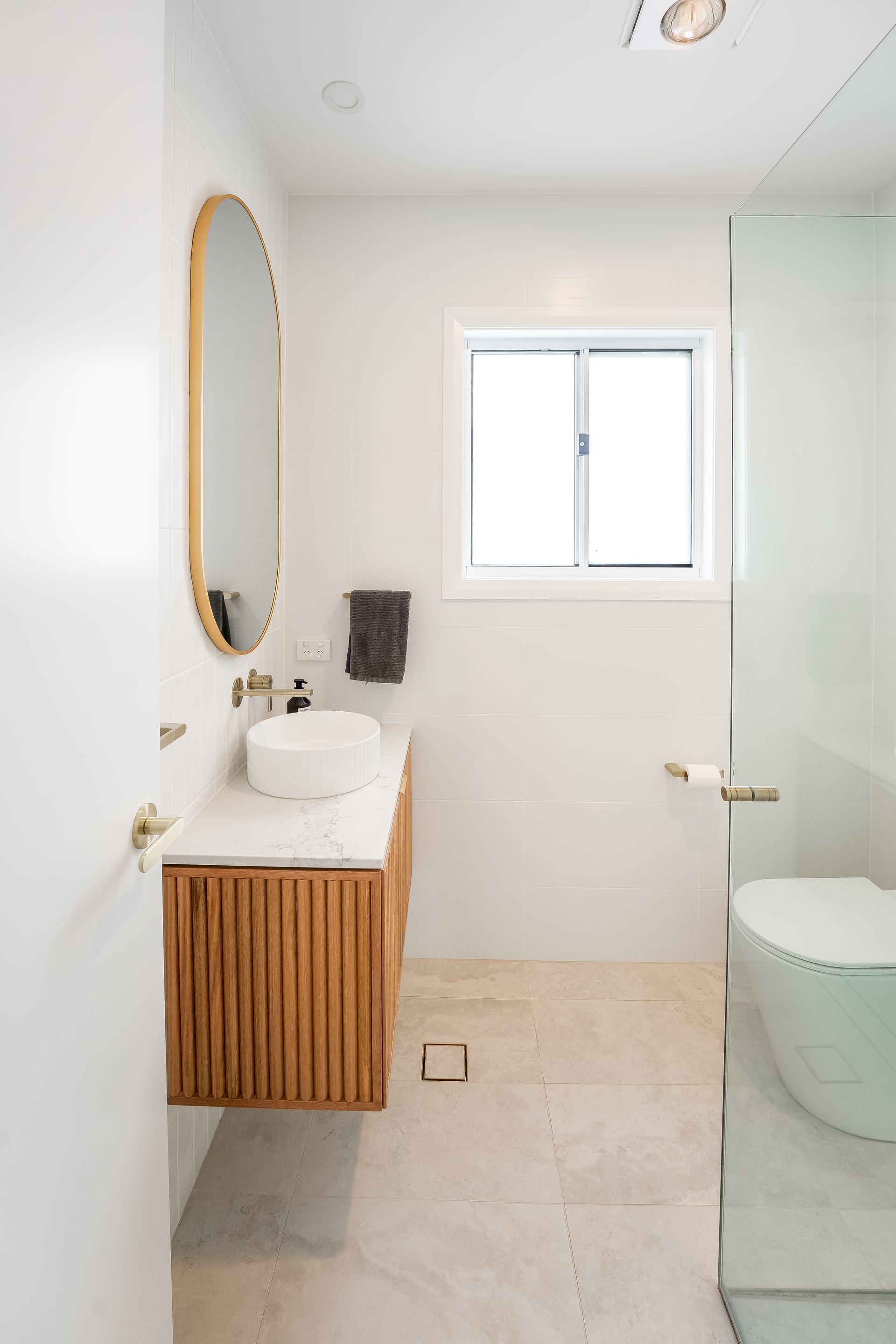Bright Minimalist Bathroom With Wood Vanity, Oval Mirror, Frosted Glass Shower — Matt Made Building in Camden, NSW
