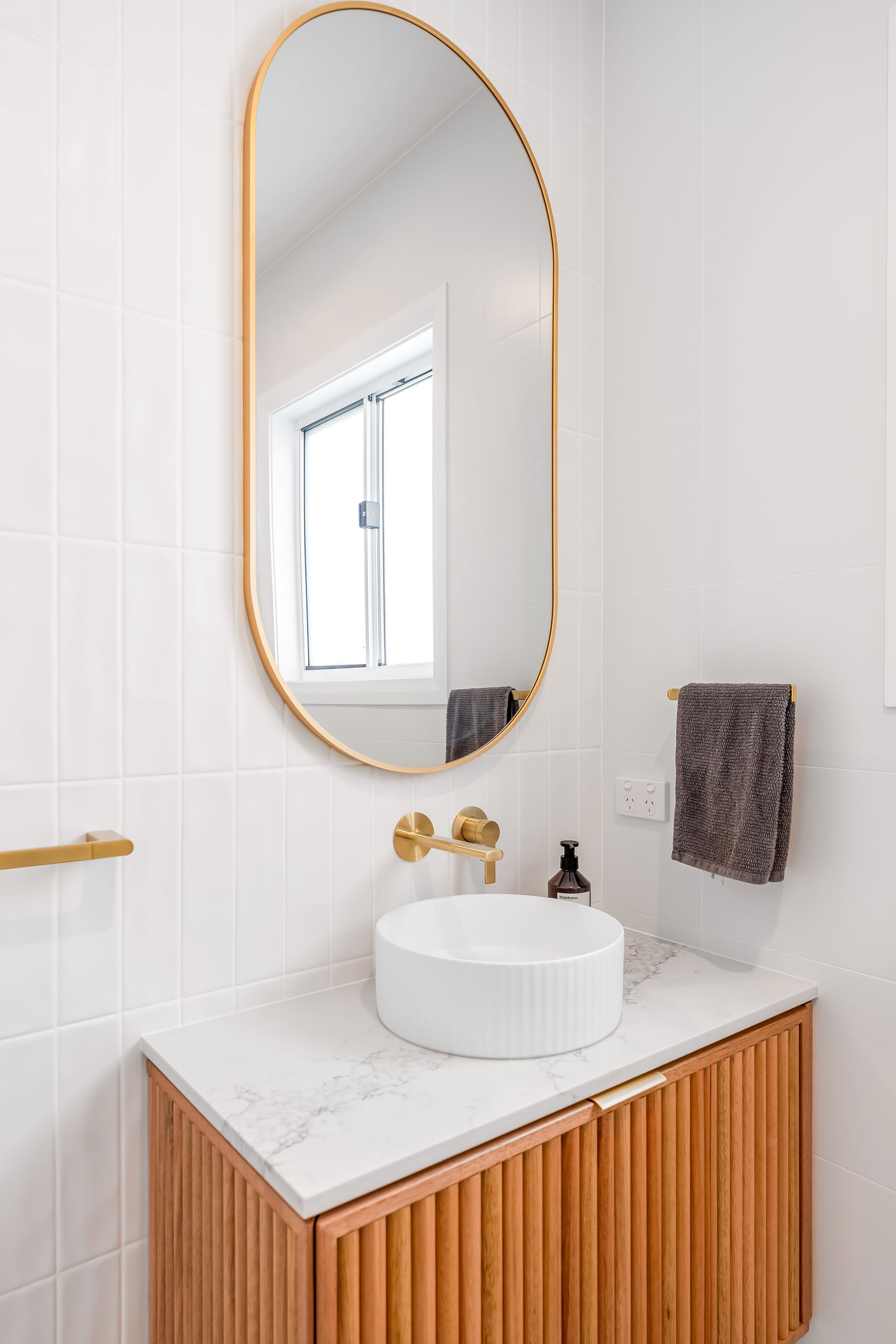 Modern Bathroom Vanity With Oval Gold Mirror and Wood Slat Cabinet — Matt Made Building in Camden, NSW