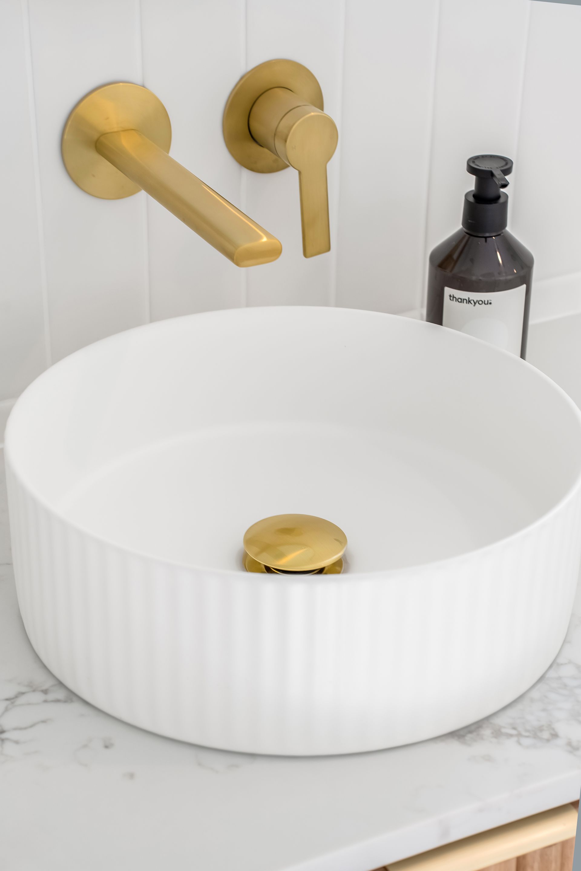 White Ribbed Sink With Gold Faucet and Drain Stopper on a Marble Countertop — Matt Made Building in Camden, NSW