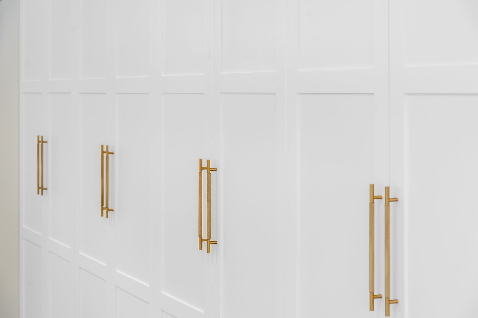 White Built-in Cabinets With Long Gold Handles in a Bright Room — Matt Made Building in Camden, NSW