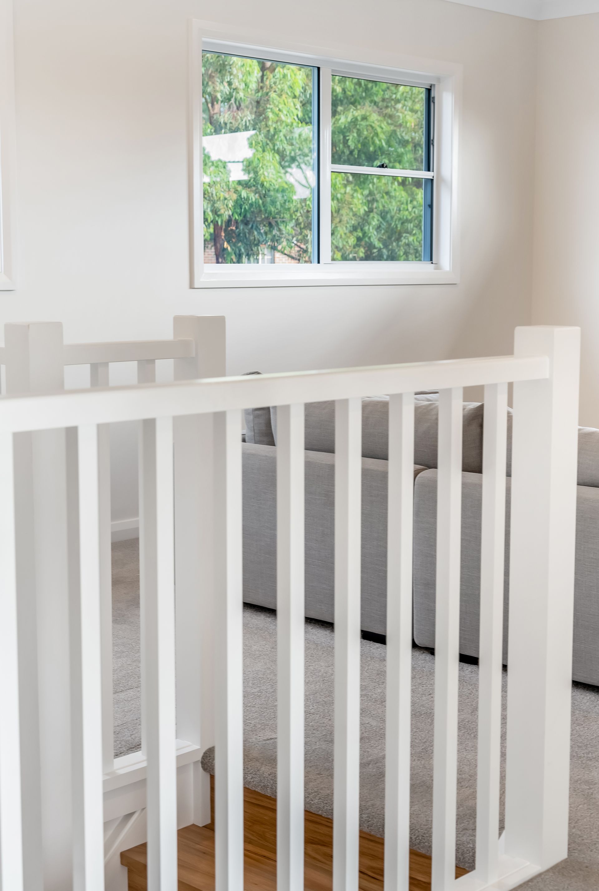 White Stair Railing in a Bright Carpeted Hallway With a Window — Matt Made Building in Camden, NSW