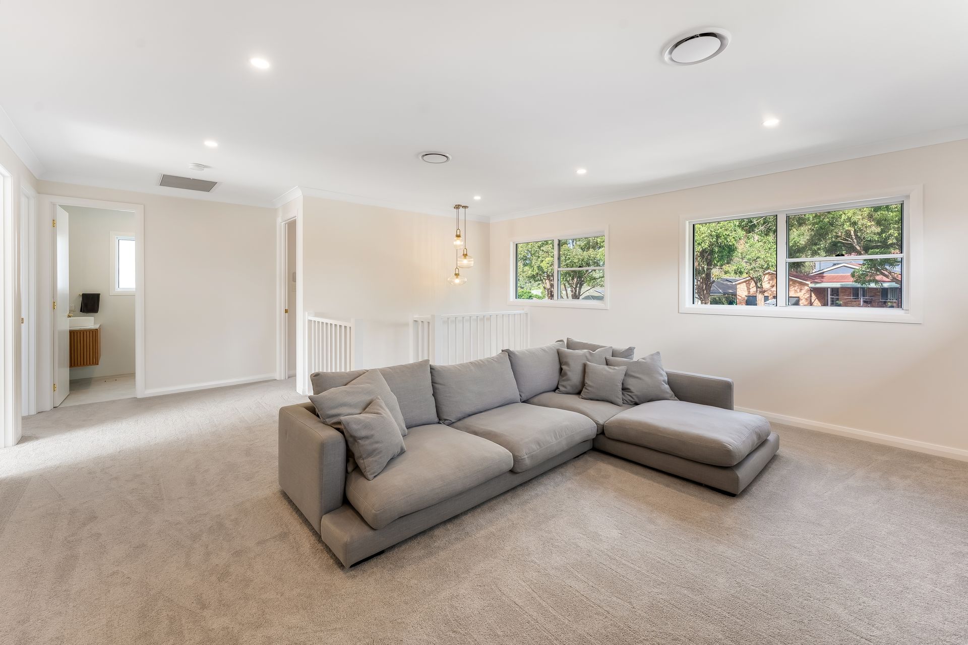 Bright Living Room With Gray Sectional Sofa and Large Windows — Matt Made Building in Camden, NSW