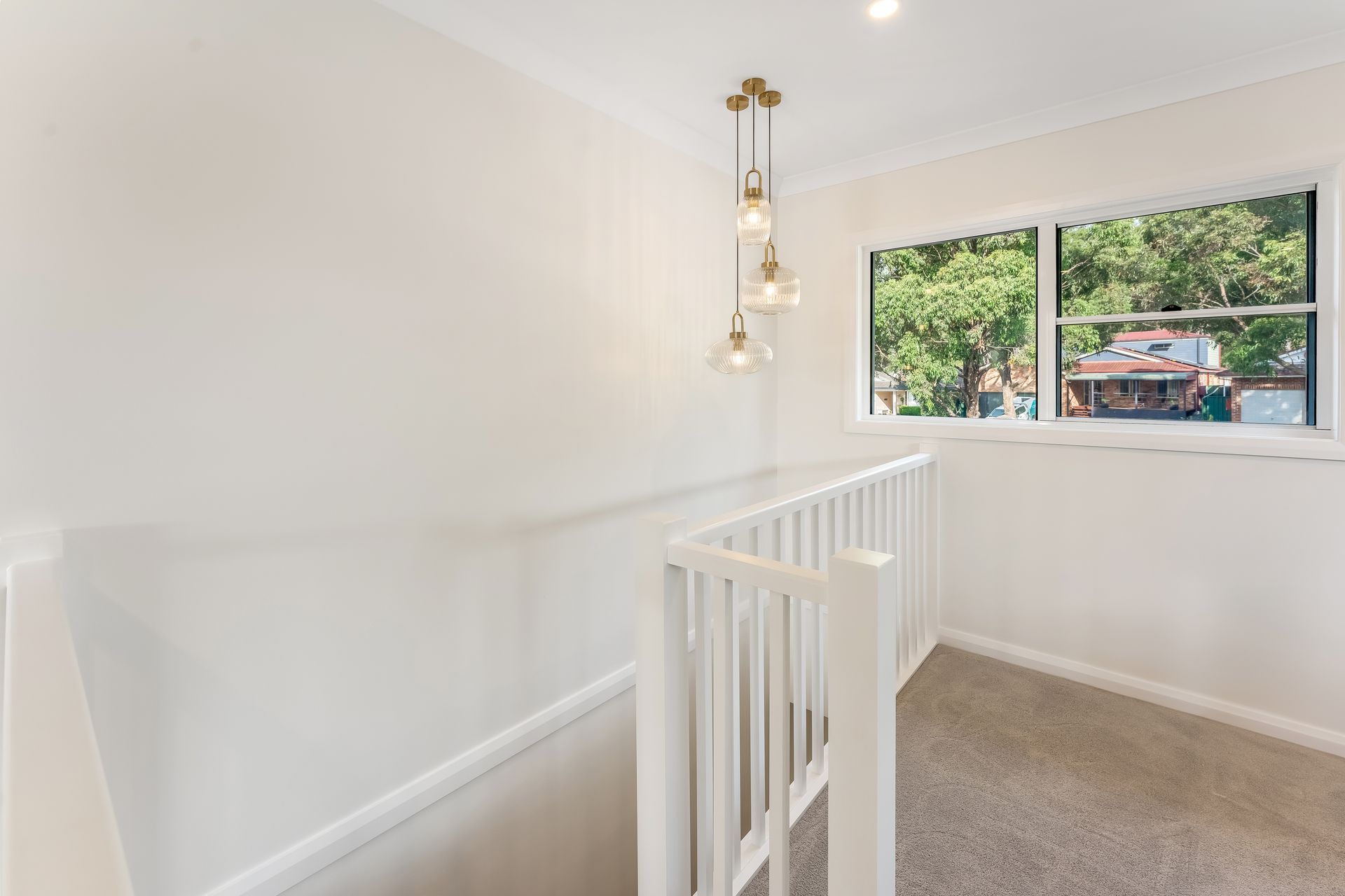 Bright Upstairs Landing With White Railing and a Window Overlooking Trees — Matt Made Building in Camden, NSW