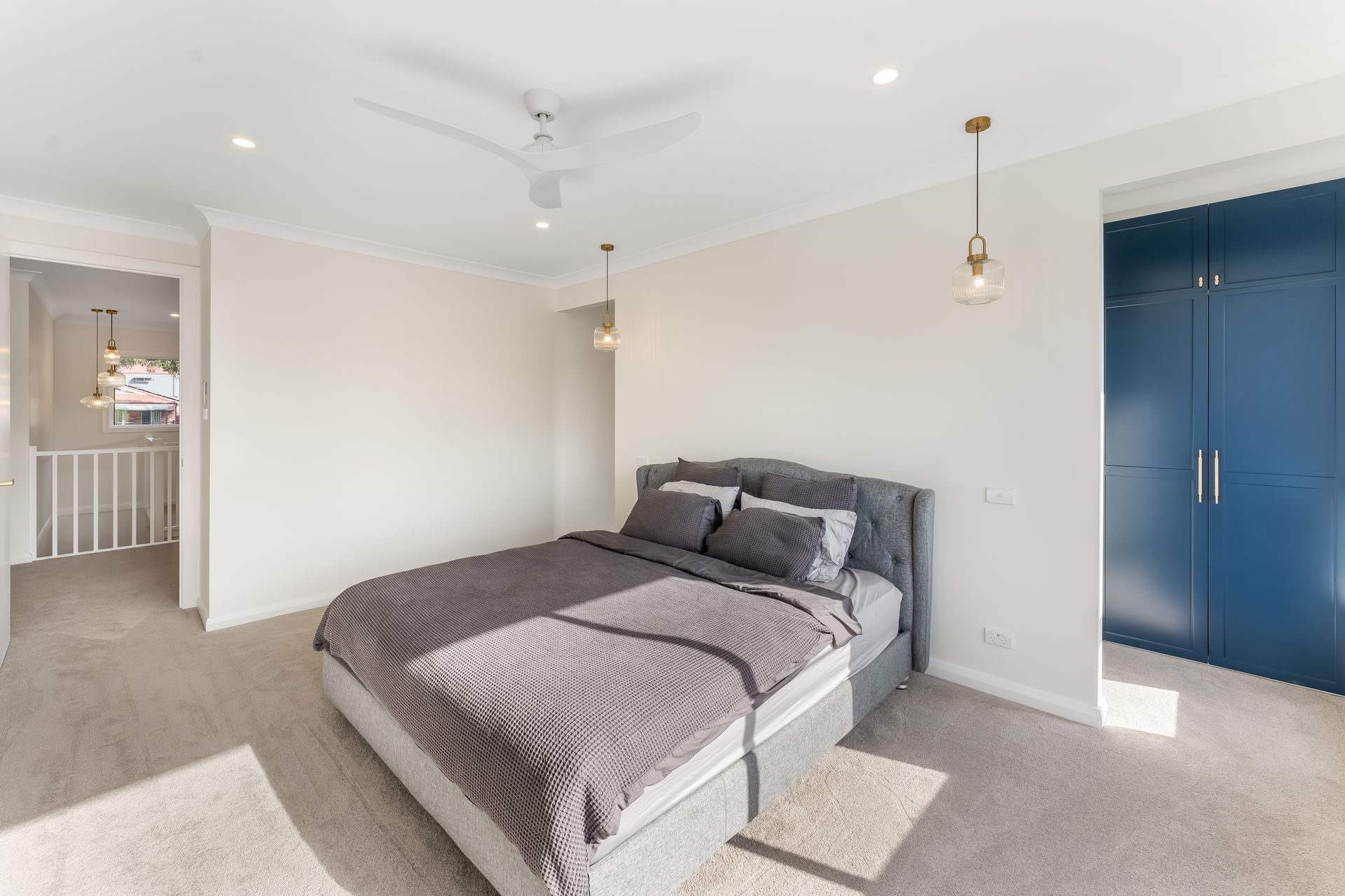 Bright Bedroom With a Gray Bed, Blue Closet Doors, and Beige Carpet — Matt Made Building in Camden, NSW
