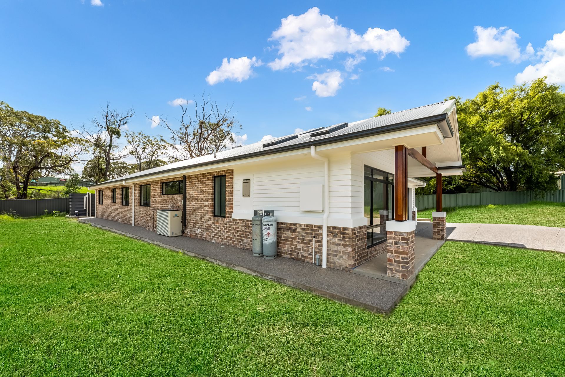 Single-story Brick House With a White Porch and Green Lawn Under a Blue Sky — Matt Made Building in Camden, NSW