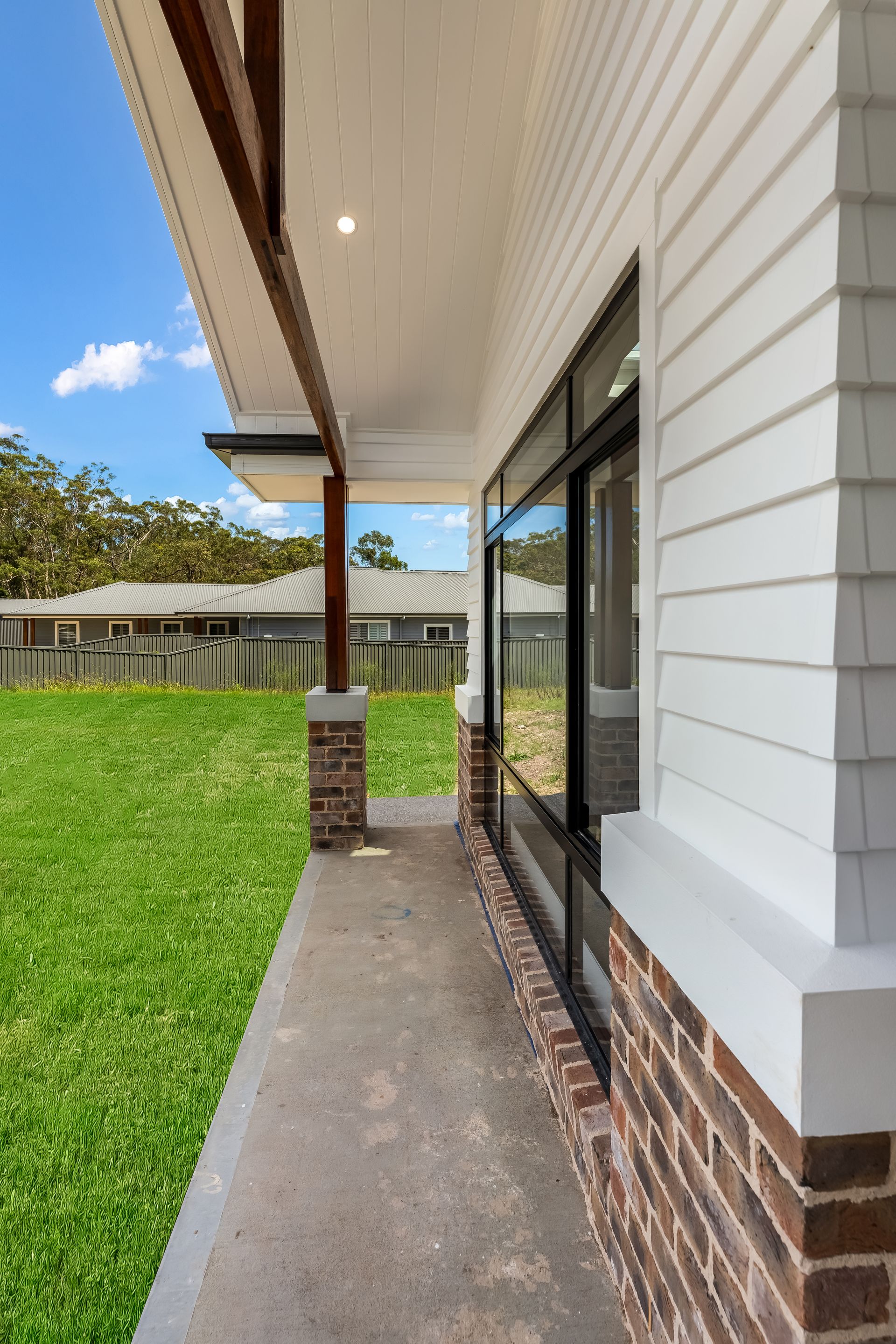 Side View of a House Exterior With Brick-and-white Siding and a Green Lawn — Matt Made Building in Camden, NSW