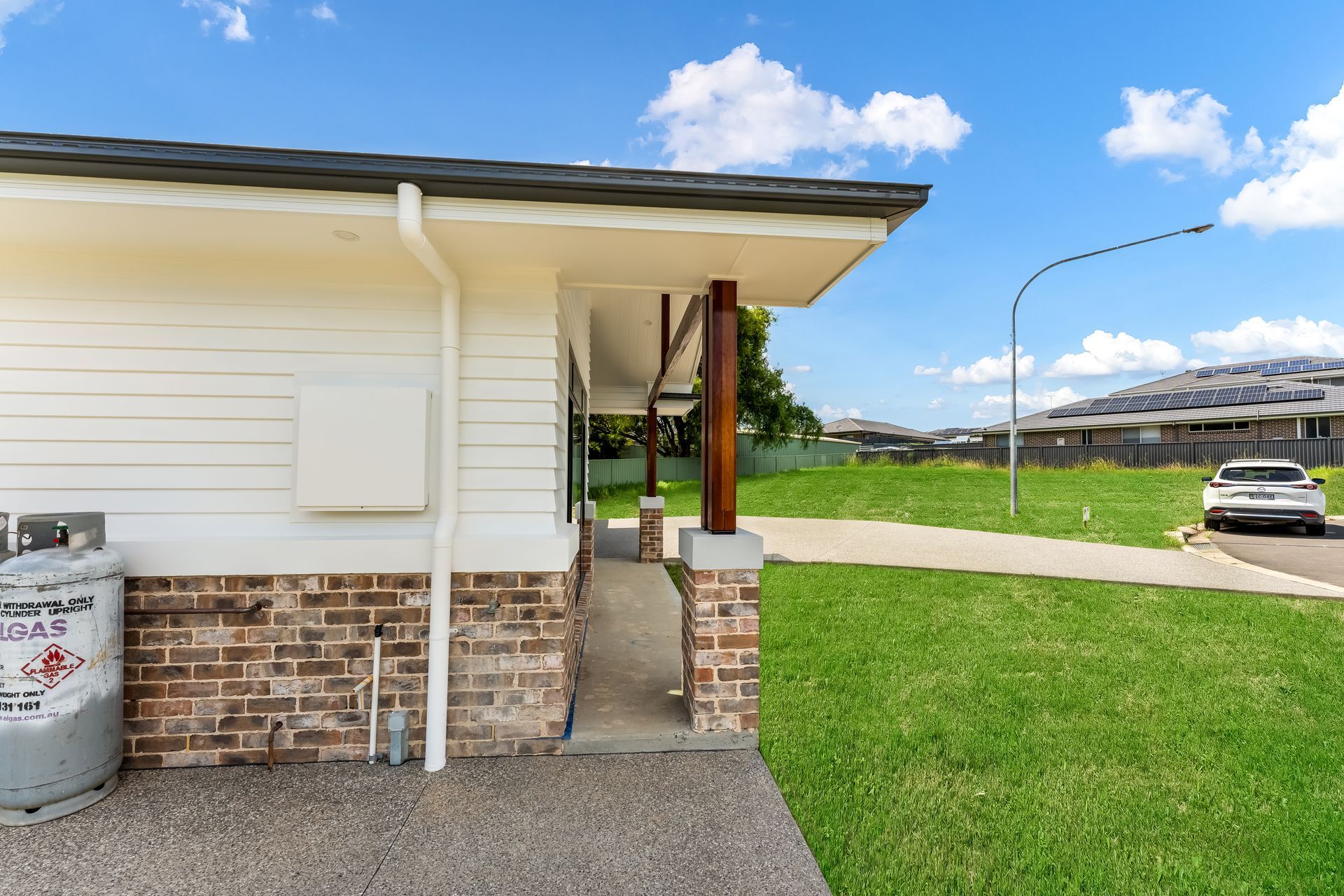 White House Exterior With Brick Base and Parked Car Under a Blue Sky — Matt Made Building in Camden, NSW