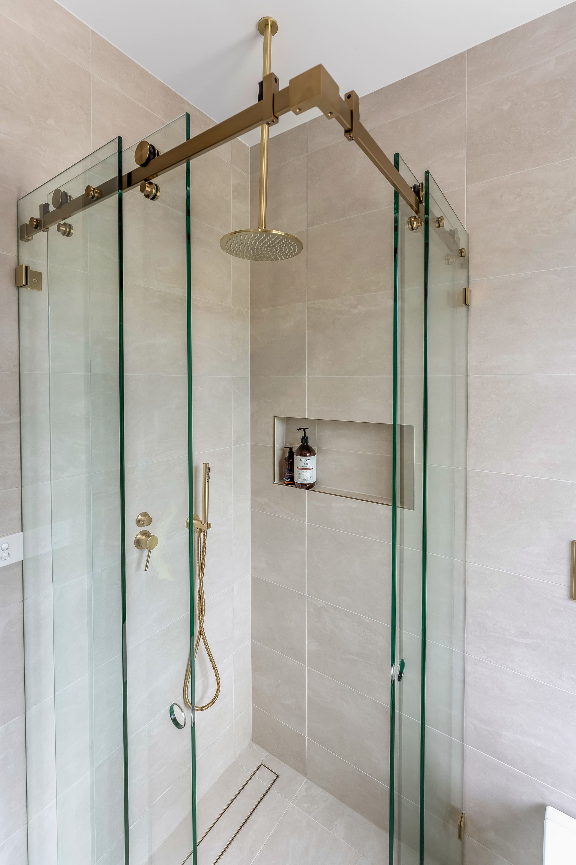 Glass-enclosed Shower With Brass Fixtures and a Hanging Showerhead — Matt Made Building in Camden, NSW