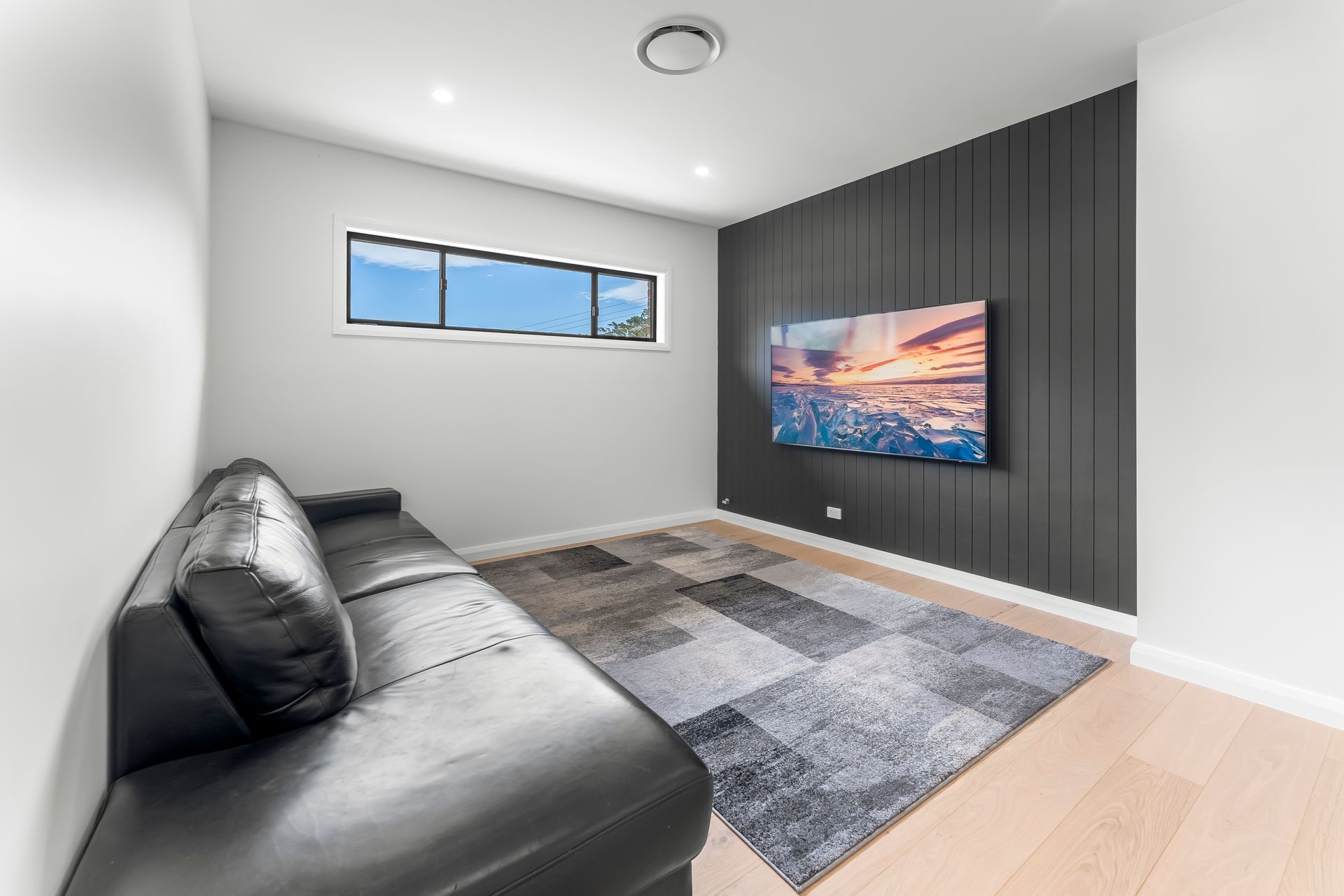 Modern Minimalist Living Room With Black Sofa and Gray Rug Under a Small Window — Matt Made Building in Camden, NSW