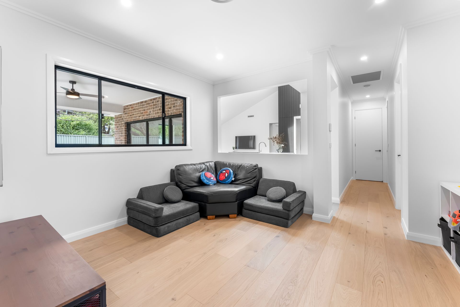Bright Modern Living Room With Black Sectional Sofa and Light Wood Floors — Matt Made Building in Camden, NSW