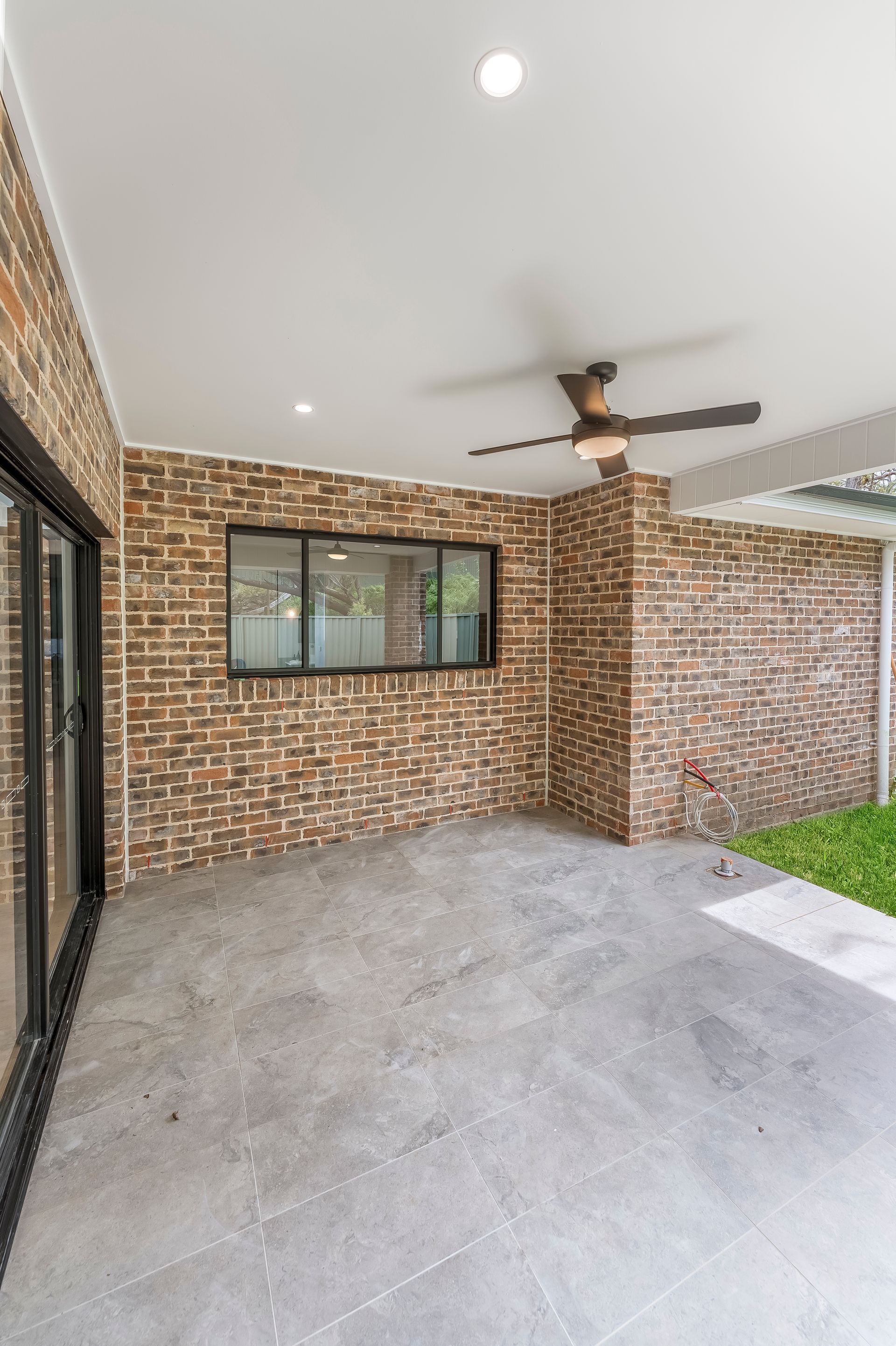Covered Brick Patio With Ceiling Fan and Tiled Floor Opening to a Small Lawn — Matt Made Building in Camden, NSW