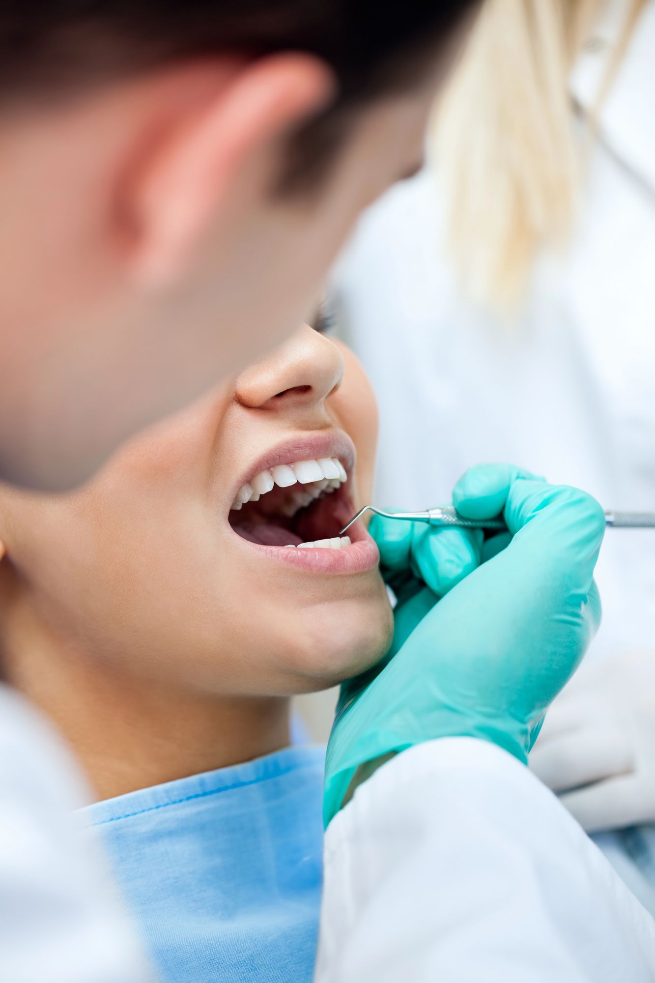 Odontólogo examinando la boca abierta de un paciente con un espejo dental y manos enguantadas.