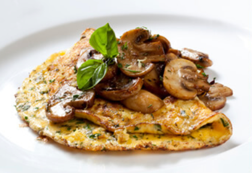 Omelet met gebakken champignons en basilicum, geserveerd op een wit bord.