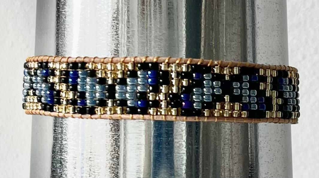Kralenarmband in blauw, goud en zwart met een sluiting.