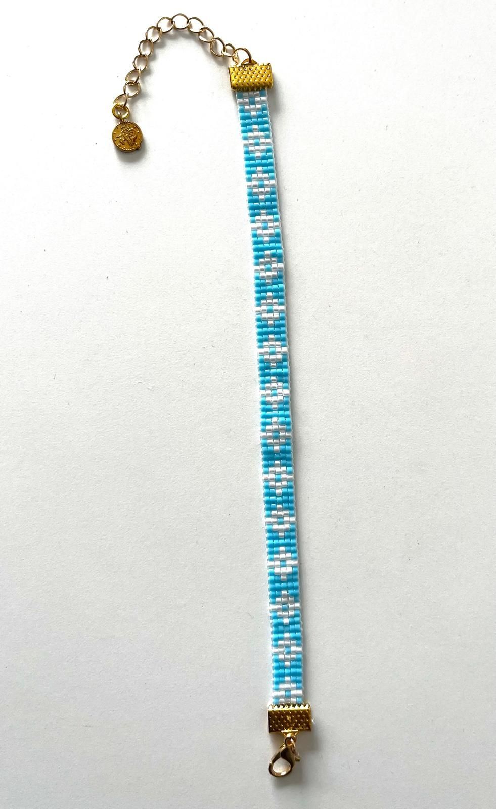 Blauw-witte kralenarmband met goudkleurige sluiting en verlengketting op een witte achtergrond.