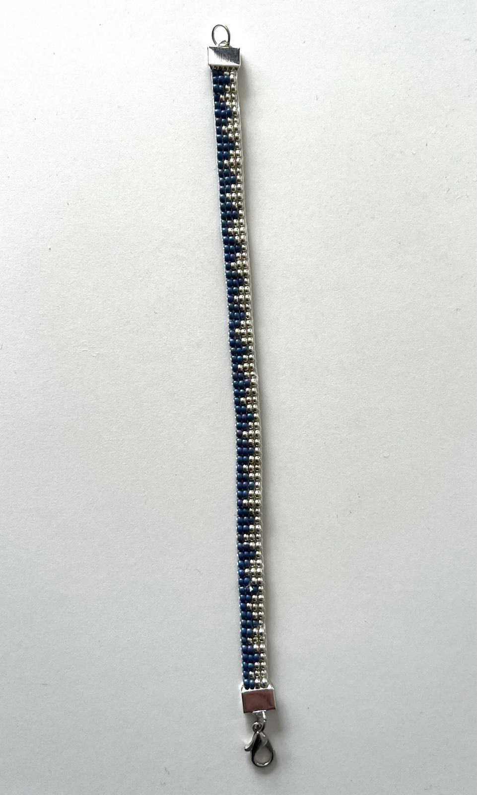 Blauwe kralenarmband met zilveren sluiting, verticaal weergegeven op een lichte achtergrond.